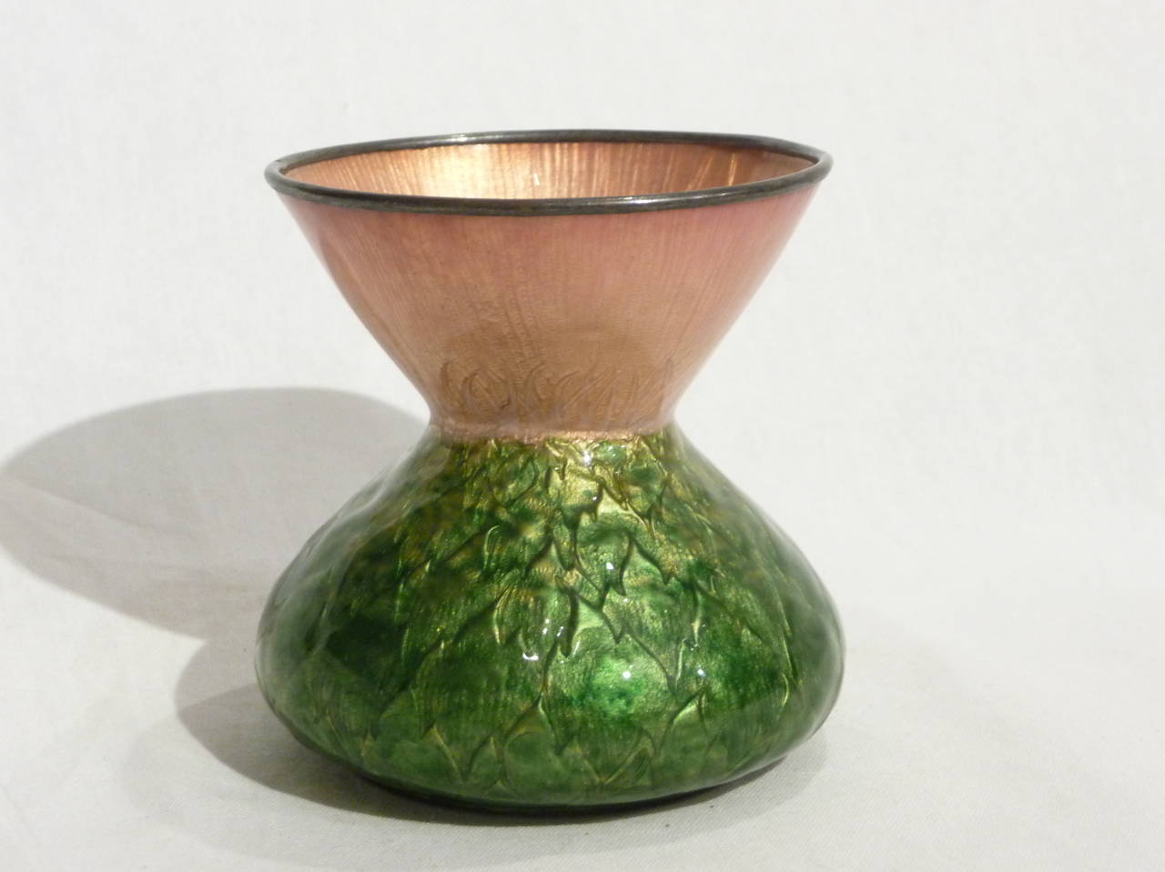 Copper and translucent enamel diabolo vase, the lower part is decorated with green enamel and gold artichoke leaves. The upper part is decorated with pink enamel. Signed. 

Identical model at the Kunstgewerbe Museum in Berlin, acquired at the