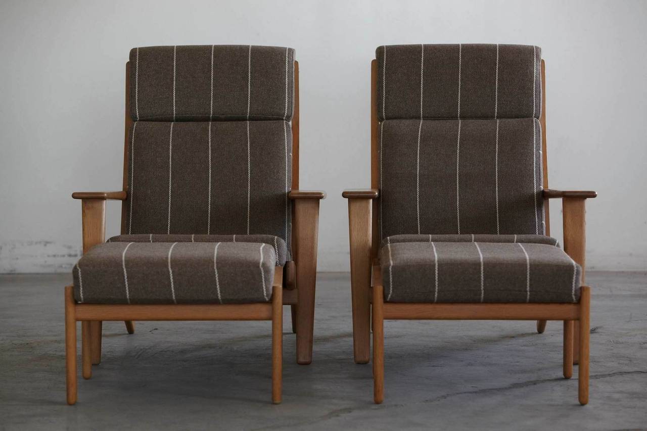 Iconic high back lounge chair model GE290 by Hans J Wegner for GETAMA with matching Ottoman model GE290A. Solid oak frame with nice patina and upholstered original cushions in Greenlandic wool.