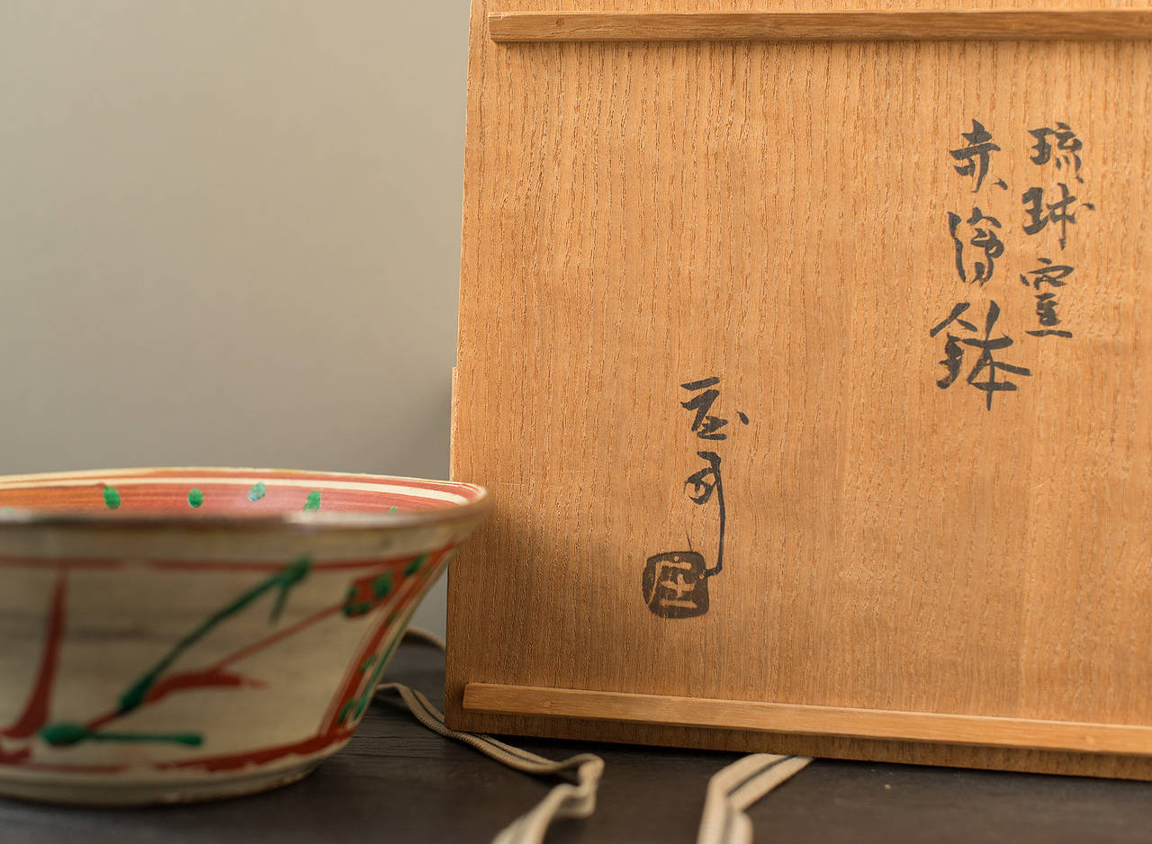 Rare Okinawa bowl 

by Shoji Hamada (1894-1978).

In signed box fitted box (lid signed by Shoji Hamada)

with colored enamel glazes over a cream glaze

stoneware.

Measure: 9 x 23 x 23 cm.
3 1/2