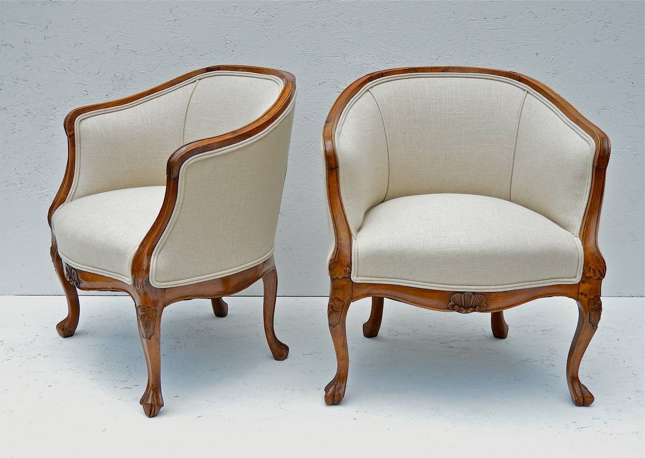 Pair of Italian slipper chairs of walnut in the Louis X taste. The finely carved and constructed frames of walnut show a wonderful patina and are highly polished. Recently reupholstered in an oatmeal linen, the chairs are in excellent condition.