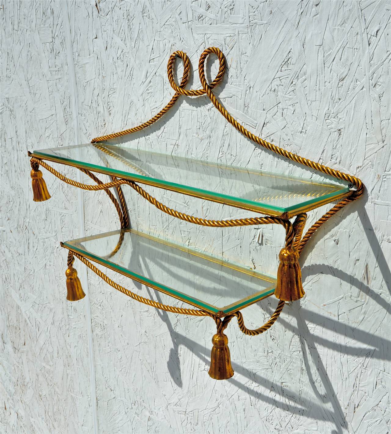 A shimmering gilt metal rope form hanging etagere having hassle form corners and two tier glass shelves, circa 1960s , Italian made.