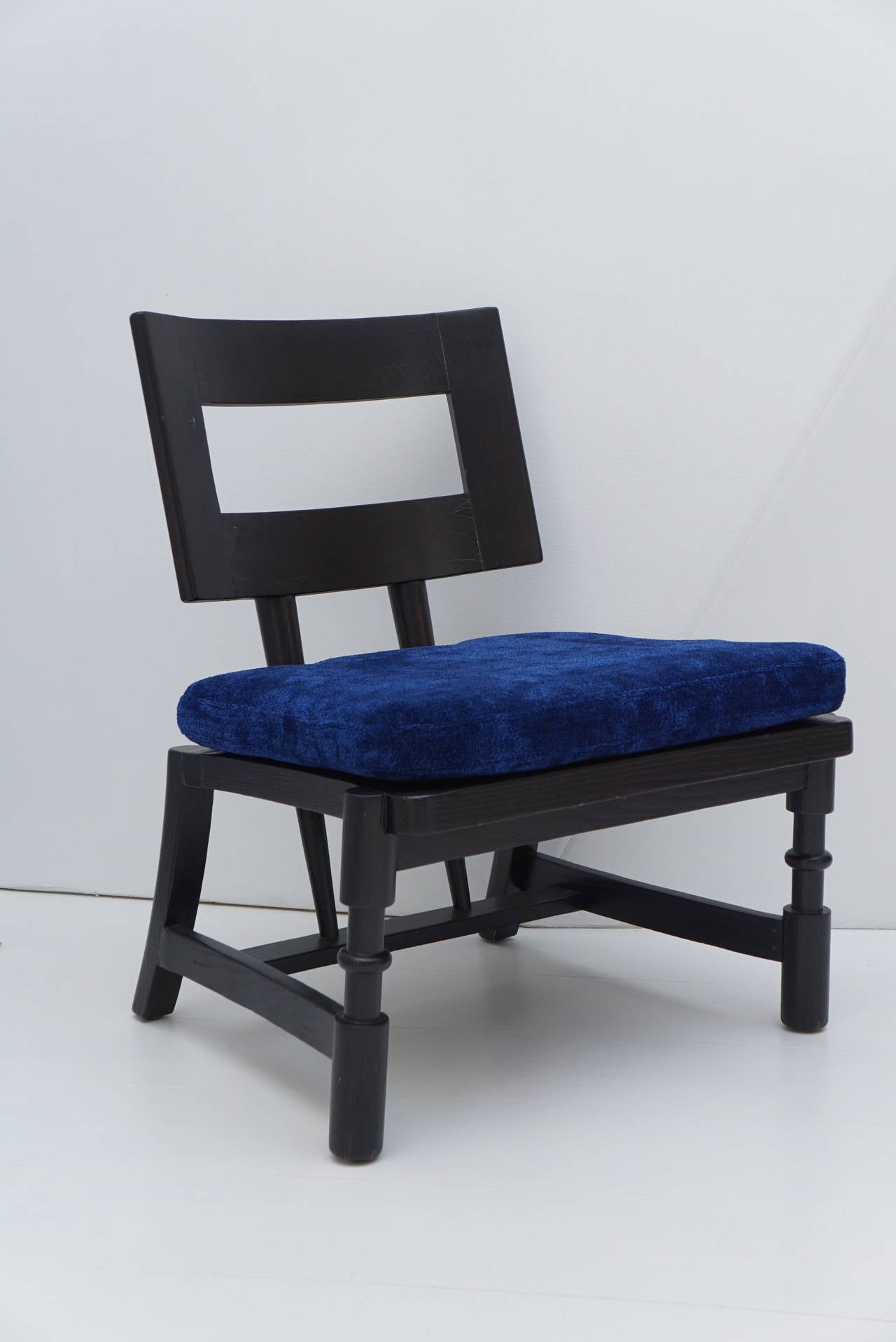 Unusual VanLeigh black stained oak lounge chair with removable electric blue seat cushion. The open frame backrest is supported by a pair of tapered uprights which pierce the seat to join the rear stretcher. The chair is a modernist take on French