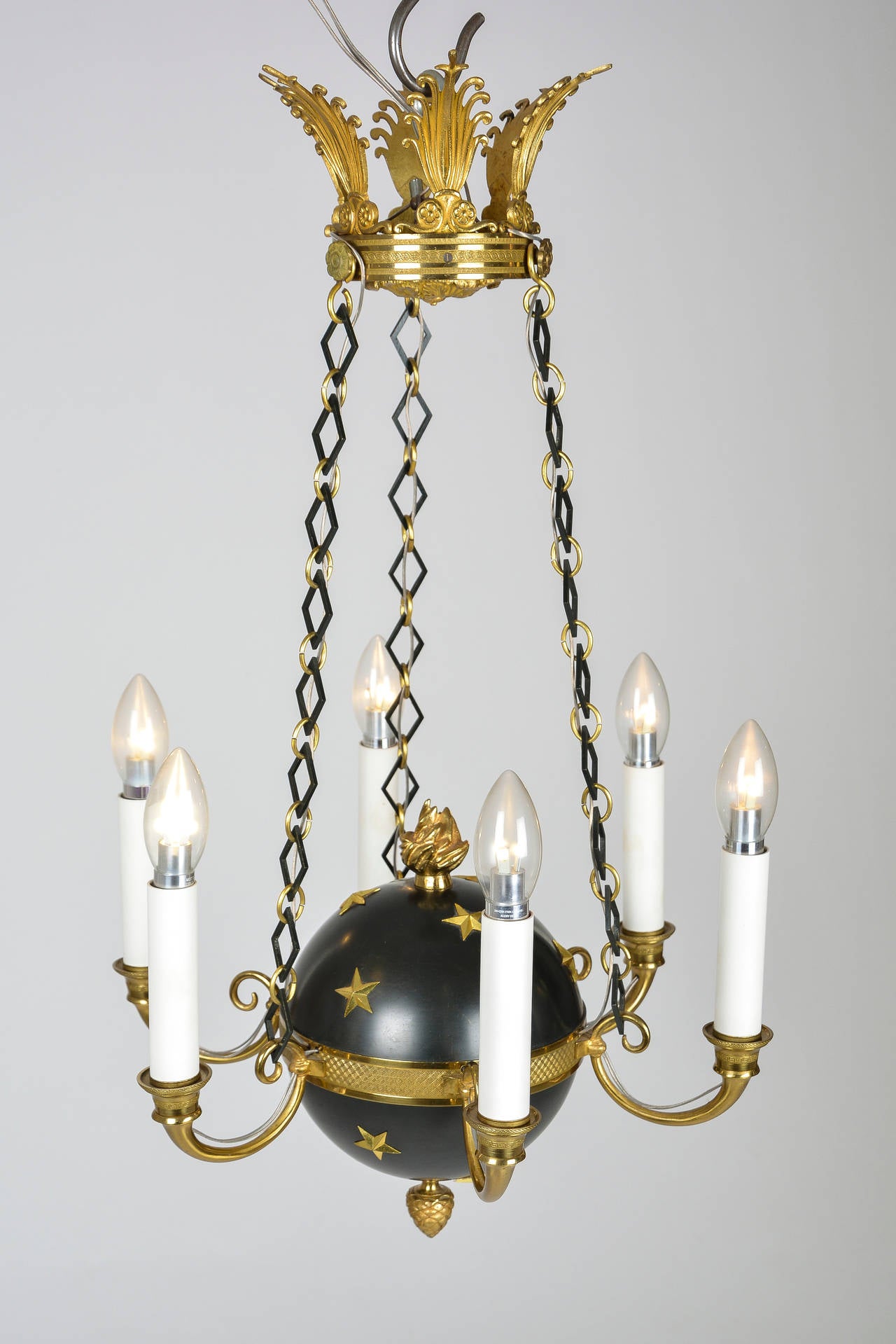 Small chandelier with stylezed celestial globe with set in stars. Made of brass, masterly embossed patinated and varnished. Rare chain details, links alternating in colour and shape. Typical cone details at bottom and flame detail on top of