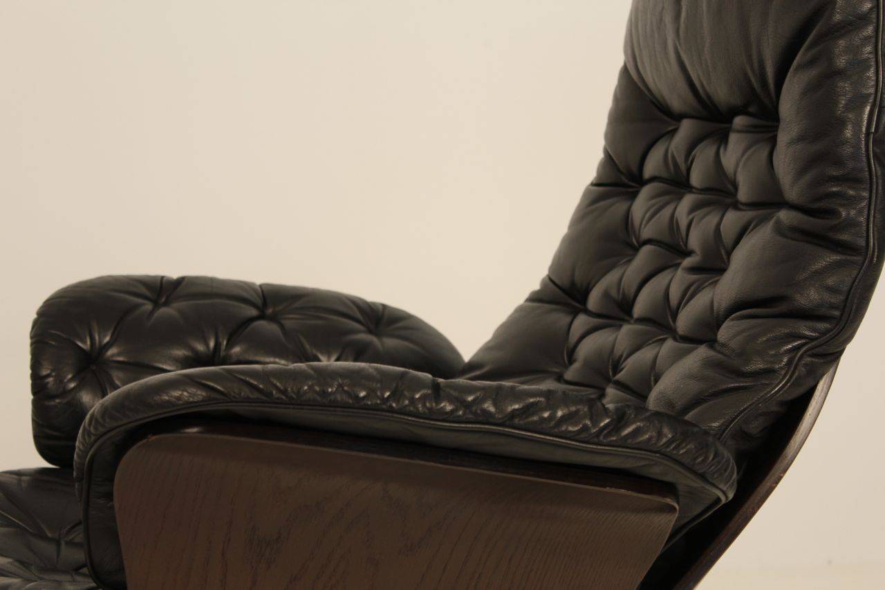 Seltener drehbarer Loungesessel, hergestellt von Göte Möbler Nassjo (G-Möbler), Schweden.

Der Stuhl hat eine geschwungene Rückenlehne aus Holz und Armlehnen, die mit geknöpften schwarzen Lederkissen bezogen sind. Der gesamte Stuhl ist in sehr gutem