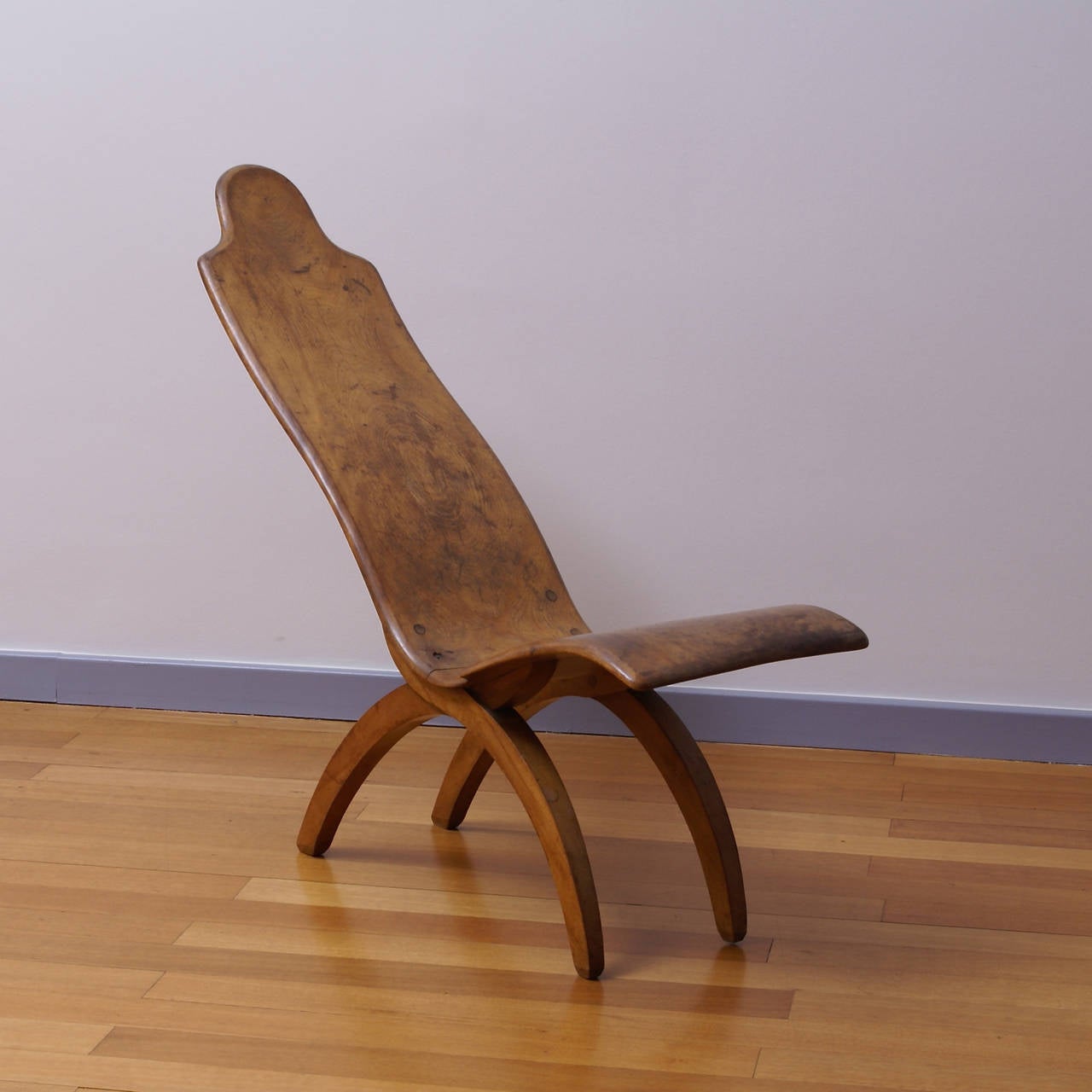 Rare low chair made of two mahogany carved parts on two X mahogany legs. Wearing underneath the label 