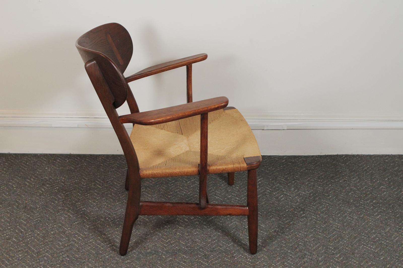 Hans Wegner for Carl Hansen and Son CH-22 lounge chair, 1950s, Denmark.
Original oak armchair with wide paddle form arms and sculpted and inlaid back. Danish paper cord seat. This sale is for one chair.
The chair was designed by Hans J. Wegner and
