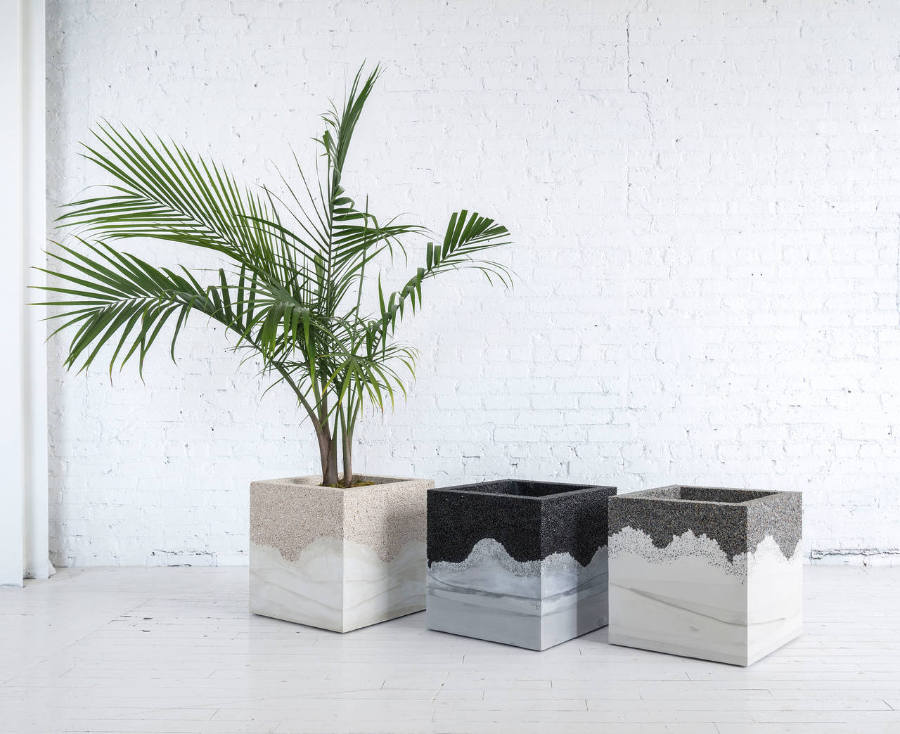 This planter consists of a hand-dyed grey cement and crushed granite. The cement is poured by hand over the aggregate, creating an organic blend between the two materials. The piece includes a drainage hole and risers for ease of movement. It weighs