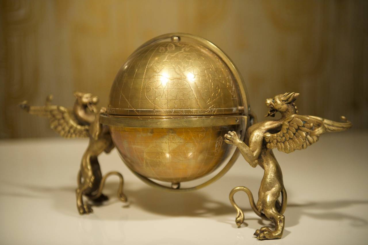 A beautifully detailed brass globe, guarded by dragons on either side. The world's continents are finely etched onto the entire surface. The top can be opened and was presumably used as an ice bucket. It measures 40cm in width and 23cm in height.