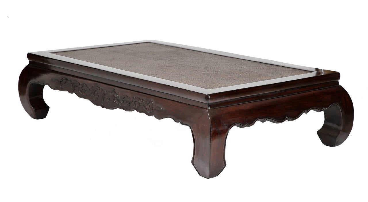 A fine example of a large daybed with a seat panel covered with woven bamboo and enclosed within a rectangular frame, above a waist and cusped aprons relief-carved on the front with intertwined foliage, supported on c-curve legs, and ending in hoof