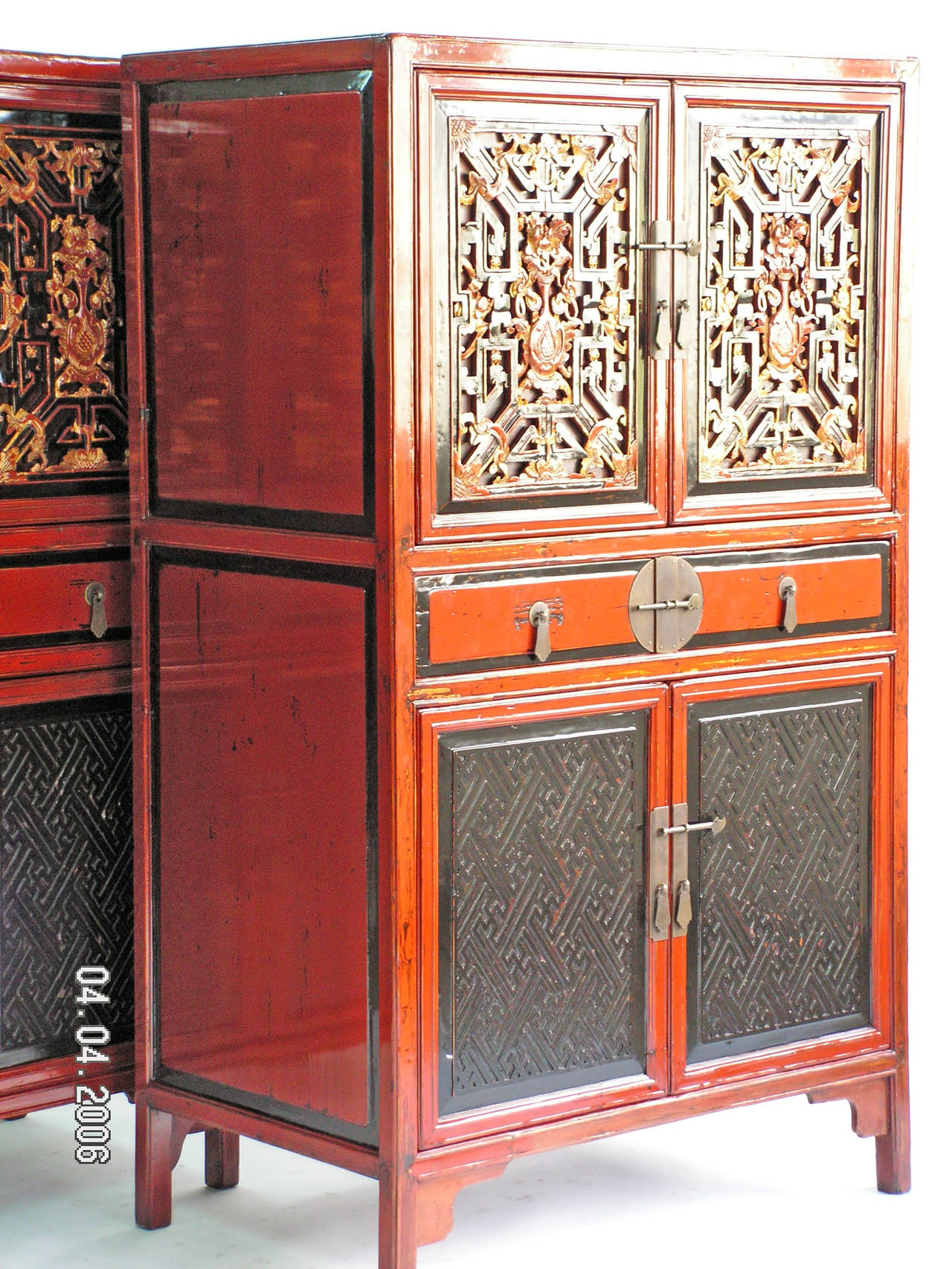 A fabulous pair of square corner cabinets covered in rich red lacquer, the upper paneled doors decorated with relief-carved gilt fretwork, scholastic flower and vase motif, and bats (good luck and fortune symbol), above two drawers, a  pair of lower