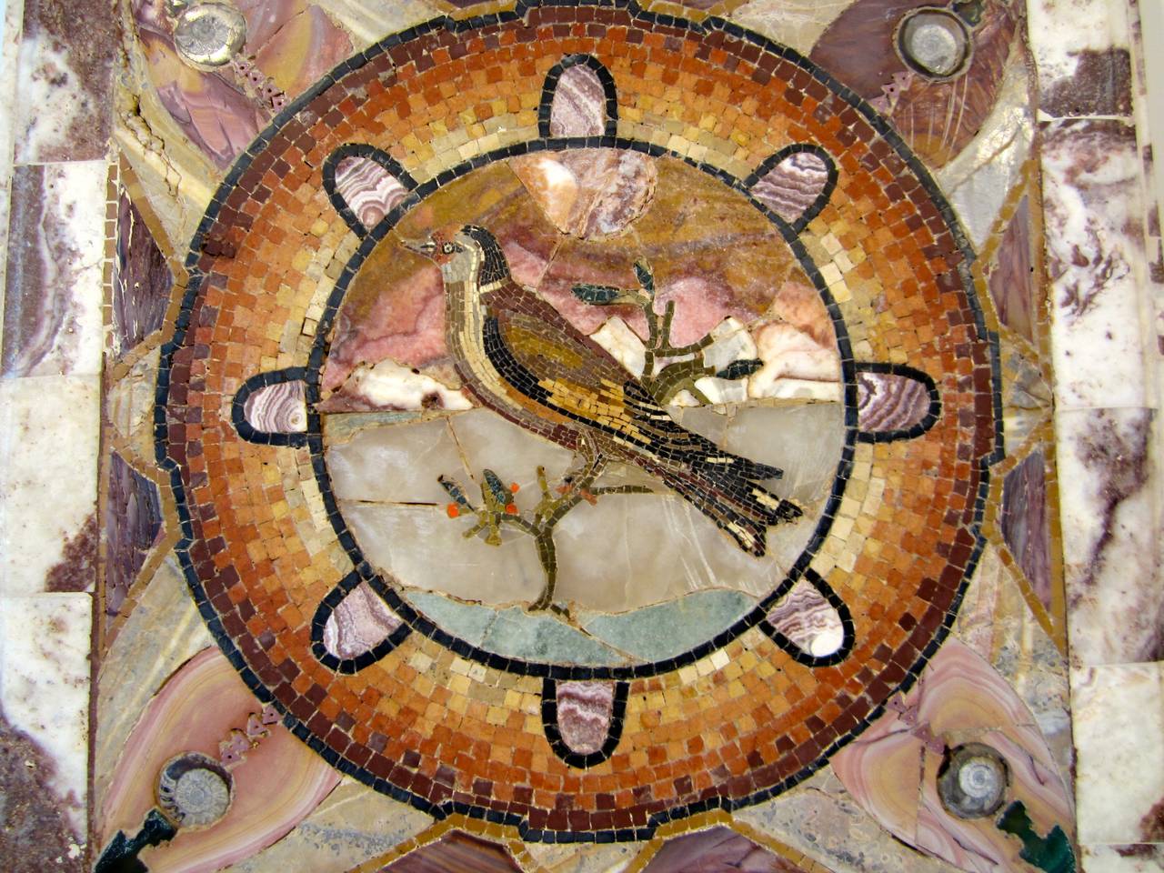 Italian marble inlaid table top made with antiques marble pieces and fossils. In the center a mosaic circle frames a micro mosaic bird, in the style of Pompei mosaico.