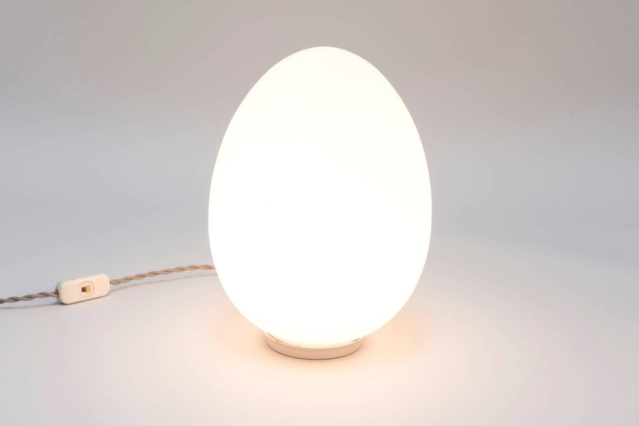 Minimal white opaque glass egg lamp in the style of Vistosi or Laurel. Opaque glass shade sits on small metal base. Unmarked. 

Original interior wiring but new twisted fabric cord.