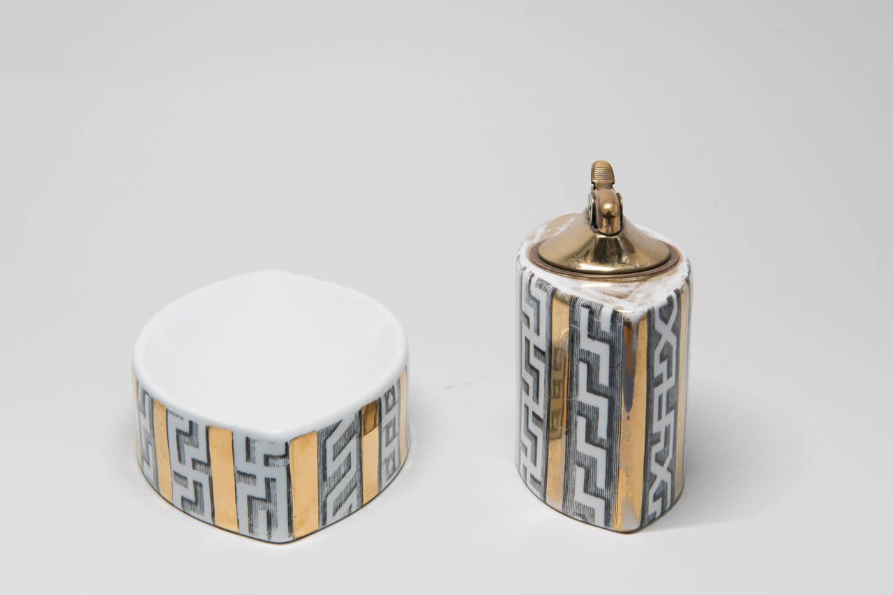 Amazing little Fornasetti smoking set from the 1950s. Set includes a lighter and ashtray. Exterior of each ceramic body with lithographically-transferred Greek key patterns and gilding. 

Underside of ashtray with Fornasetti Milano mark. Lighter