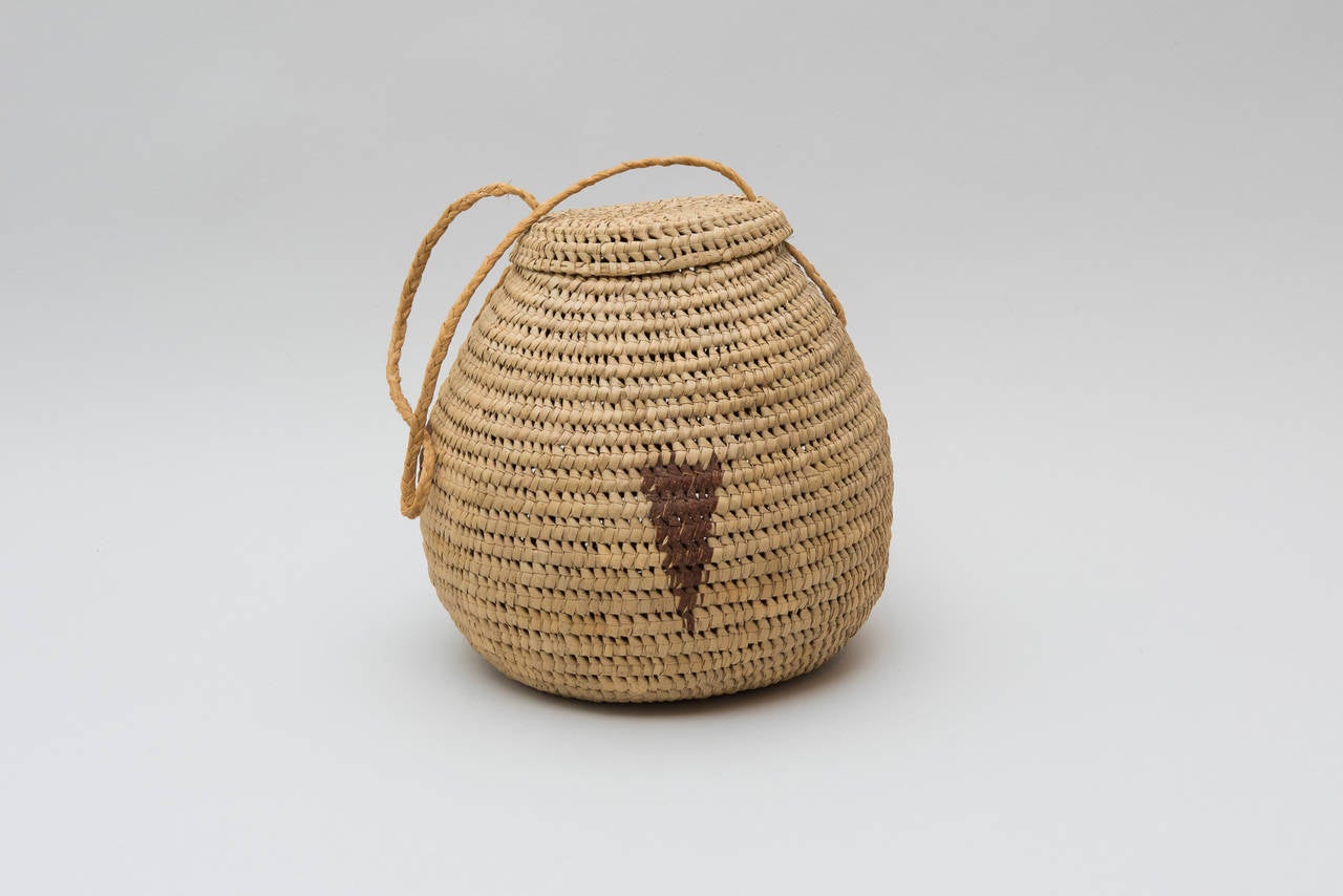 Very interesting lidded basket form with interwoven, triangular detail in rust-colored straw.  

Basket measures 10 in. high by 10 1/2 in. diameter. The handle has a drop of 12 in.