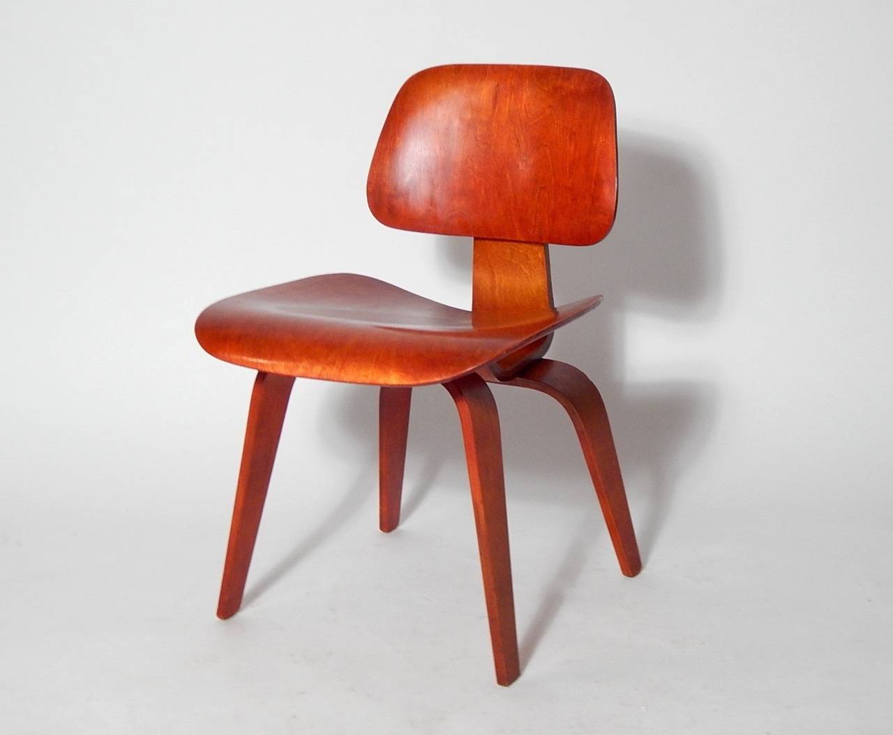 A very strong example of the early Eames design for Herman Miller, the classic DCM - in birch plywood with the less common Red Aniline, oval back shock mount, 1950s.

Marked on seat bottom with model number 1051
