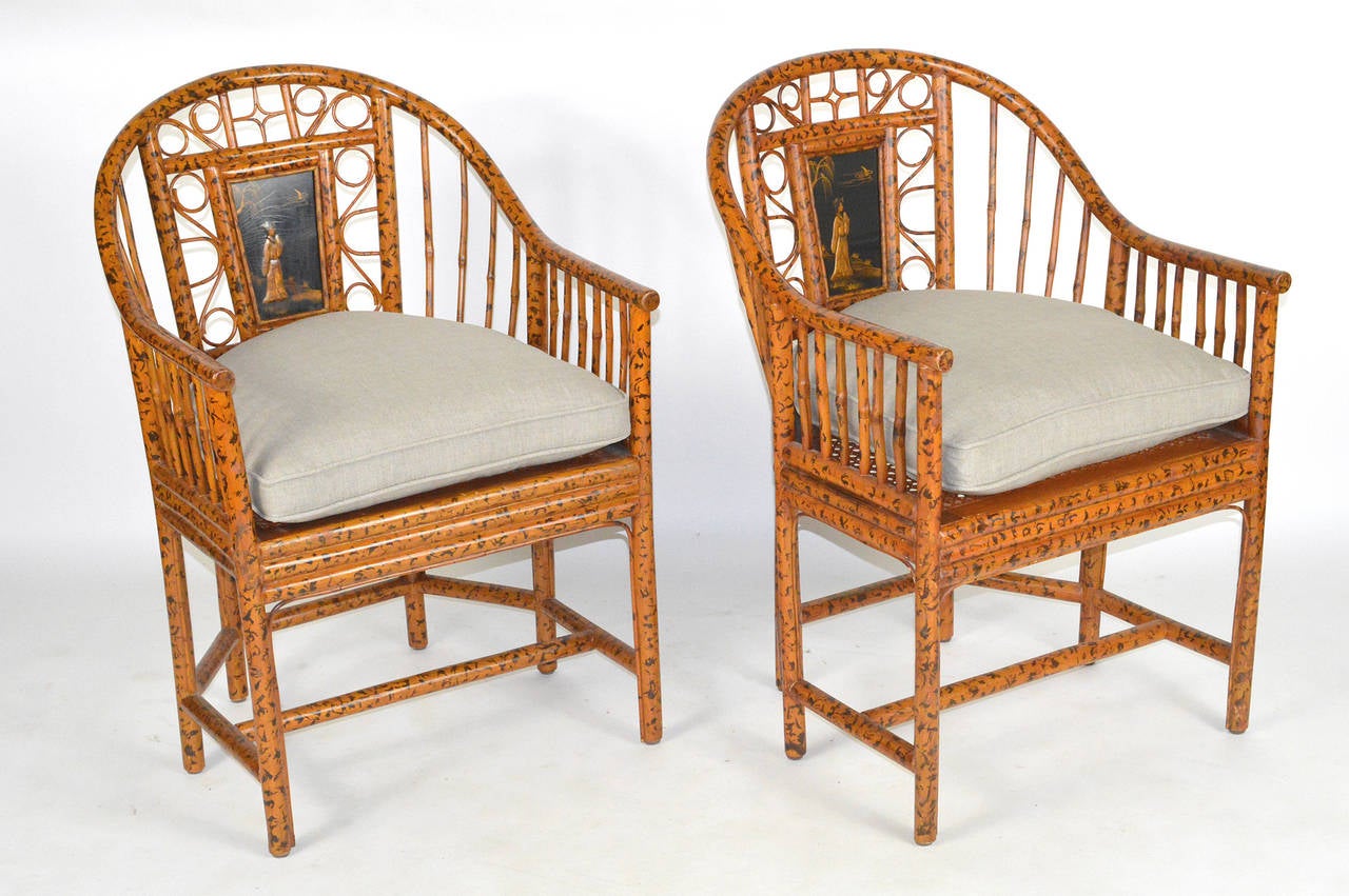 A lovely pair of Bamboo Chinese export style Brighton Pavlliion chairs. Each with rounded back. Inset with a laquered panel. Raised on straight legs, joined by stretchers. Having a loose cushion, covered in linen. Circa 1950