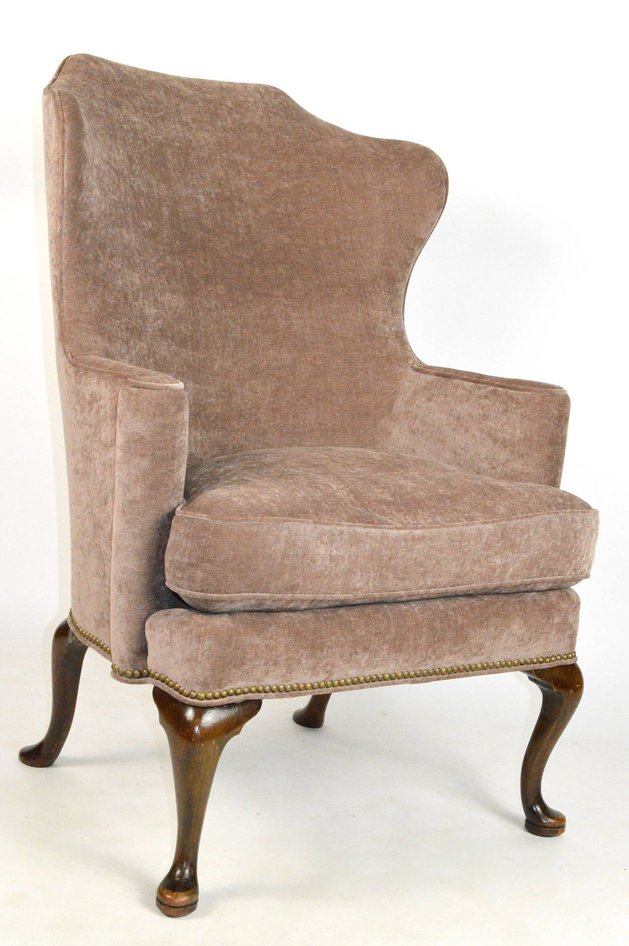 A handsome George II style walnut wing chair. Having a high curved back and out scrolled arms. Finished with nailhead trim. Raised on cabriole legs with pad feet.