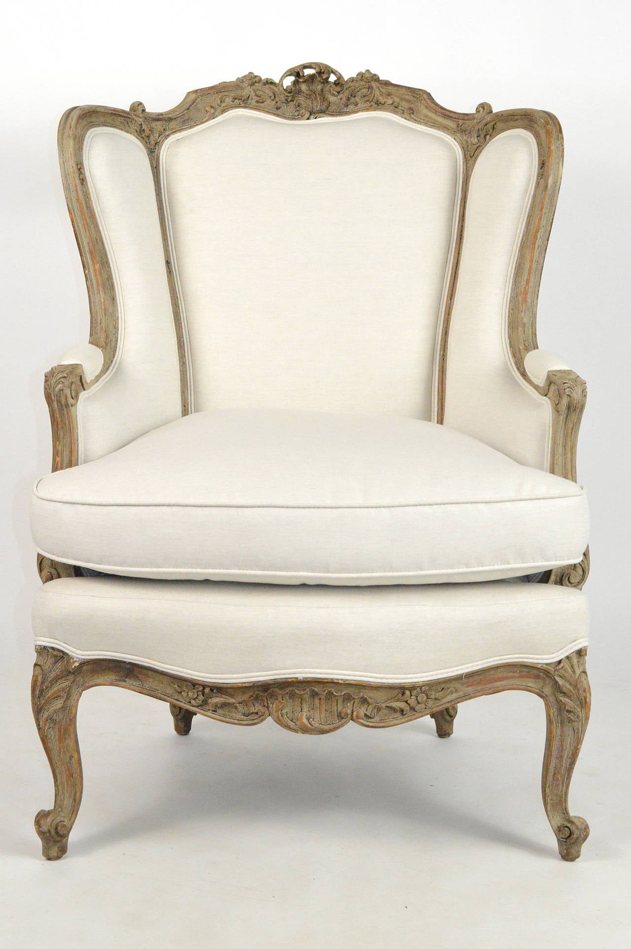 Beautiful early 20th century, French Louis XV Style painted wingback armchair. Having carving throughout the frame. Raised on cabriole legs, and covered in Linen.
