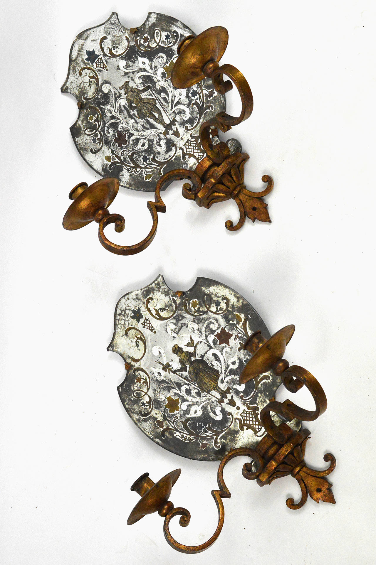 Pair of Venetian style mirrored two-arm wall sconces. Each reverse painted, one with a male figure, the other a female figure, on a shield shaped mirror. Held in a iron frame, circa 1940.