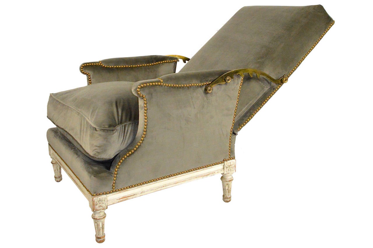 19th century, French Louis XVI reclining armchair with adjustable brass ratchet supports on carved legs with carved decoration, flanked by raised rosette corner blocks. Upholstered in dark grey silk velvet, with a loose cushion.