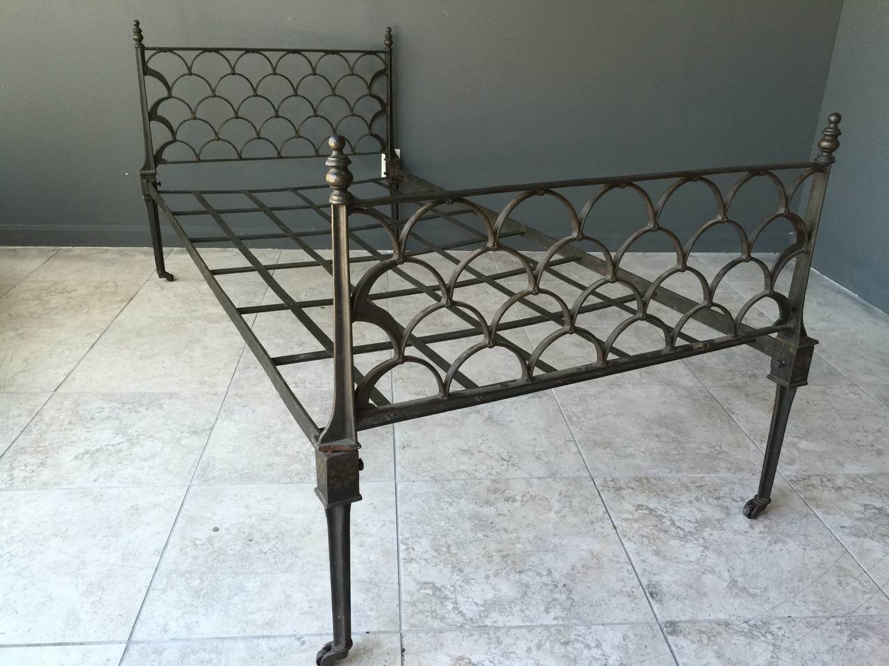With an open work stylized ginkgo leaf design in the headboard and foot board, this mid 19th Century English cast iron campaign style bed is at once modern and antique.  The iron strapping bed base slides into mounts on both the headboard and