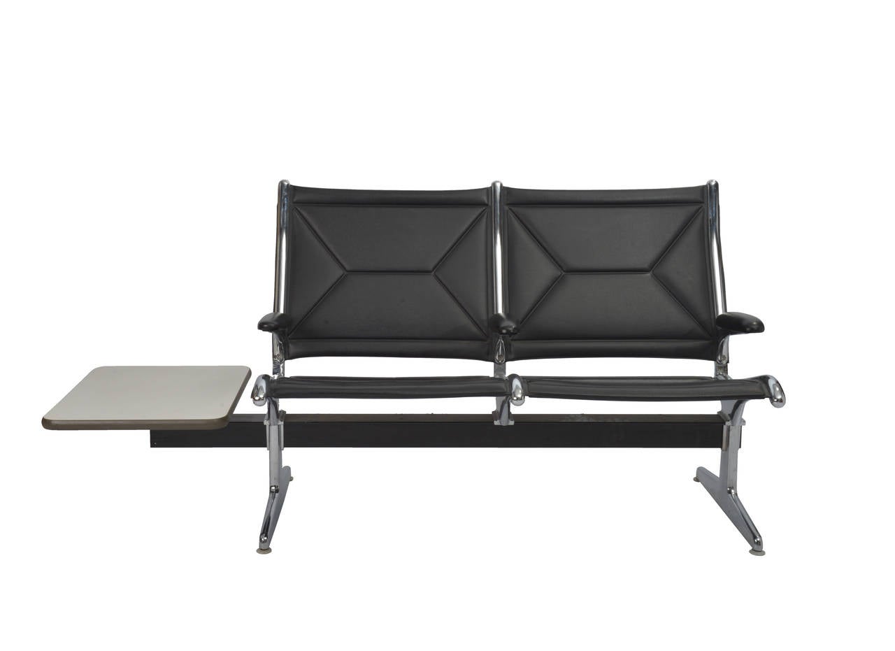 A Mid-Century Modern tandem seating chair designed by Charles and Ray Eames and made by Herman Miller. Aluminum frame newly polished and new black leather upholstery, with table.

Ray and Charles Eames were commissioned to design the perfect