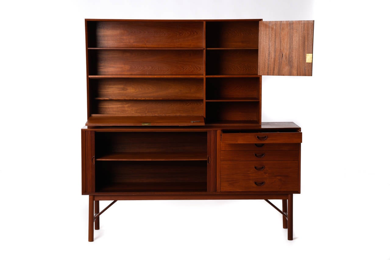 Two-piece, storage in solid teak with adjustable shelves.

Lower cabinet: Server with tambour doors and signature Hvidt pulls on doors and drawers. Top drawer is felt-lined and compartmentalized. 
Dimensions: 65.5" W x 19" D x 34"