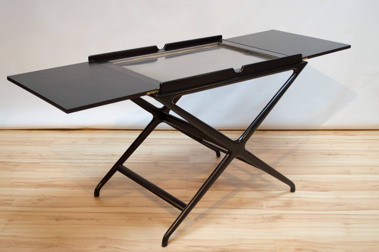 Ebony finish dry bar or tea cart by Cesare Lacca for baker with fold-out top, circa 1950s. Removable interior tray is stainless steel that sits on a cork pad. Newly refinished.