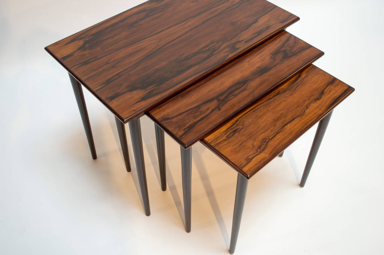 Set of three rosewood nesting tables by Westnofa of Norway. The smaller tables slide into runners in the larger table for storage, allowing the tables to easily slide together and apart.

Medium table measures 19.75