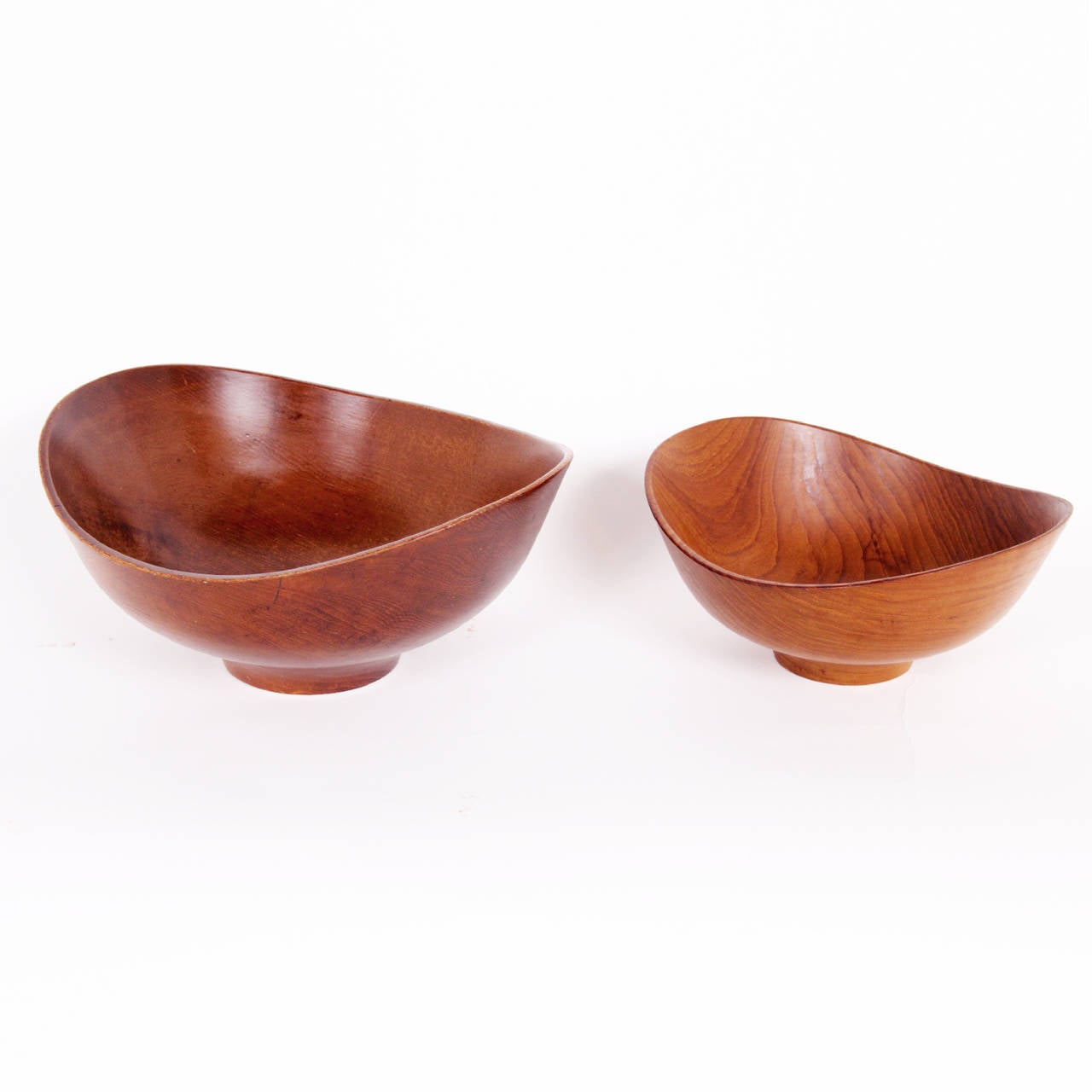 Two sculptural serving bowls made from one piece of turned teak.
Designed by Finn Juhl and manufactured by Kay Bojesens workshop.
Impressed with manufacturer's mark to underside of each example: [Kay
Bojesen Denmark Design Finn Juhl Teak].
Size