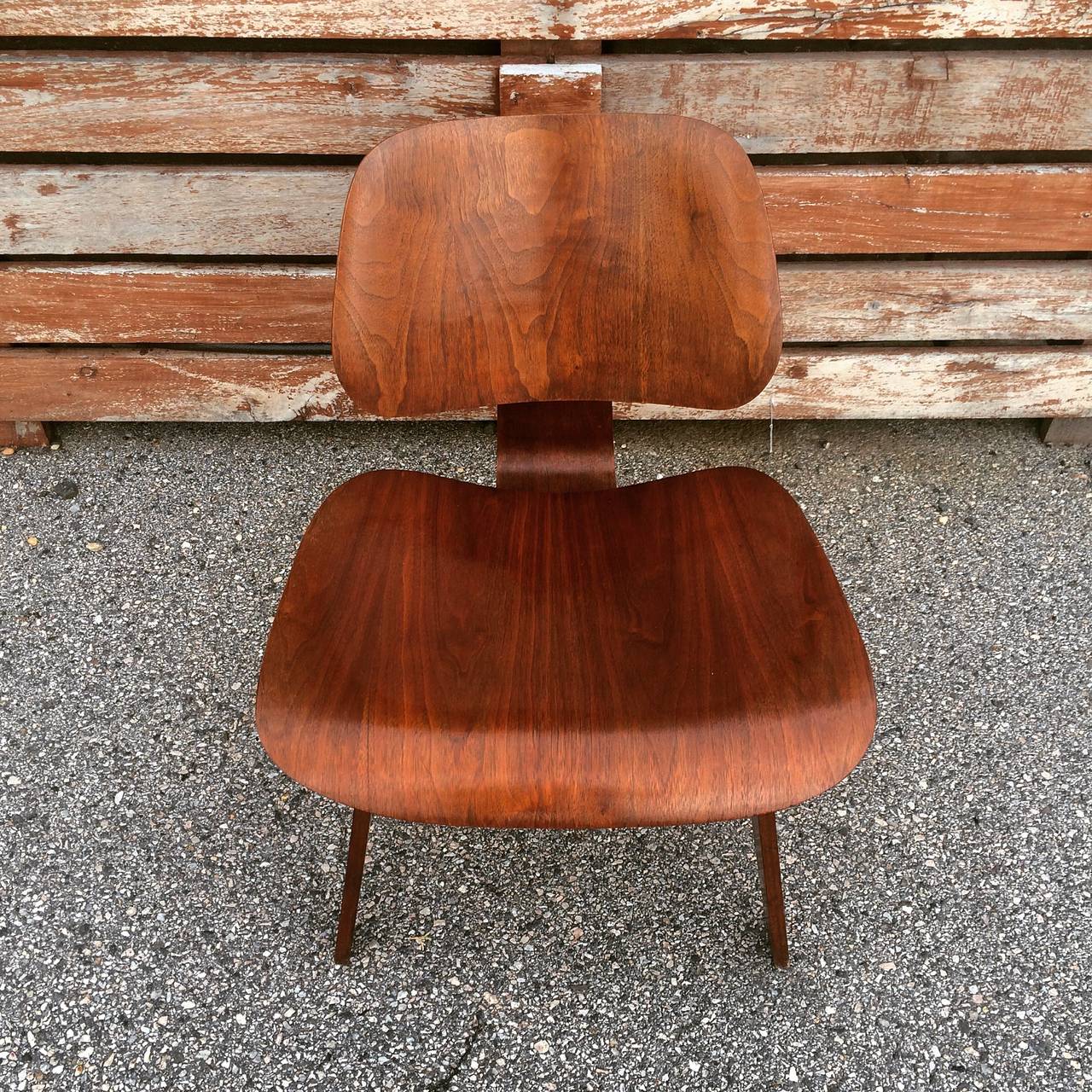 Early Eames walnut LCW by Evans Products. Dates to approximately 1947 based on label. Original shock mounts. In original condition with exceptional patina. No damage to the wood veneers. Highly figured grains and warm rich tones.