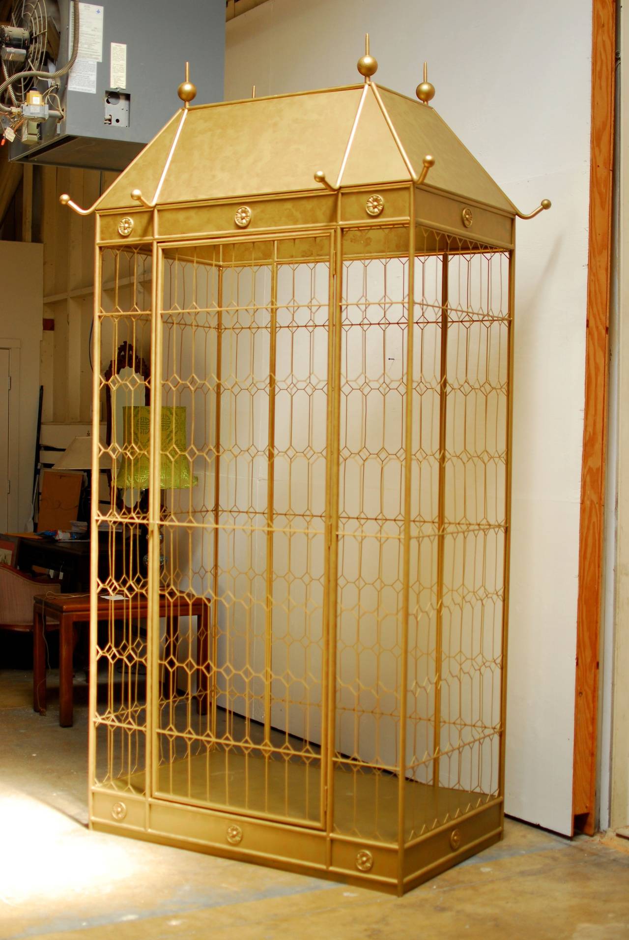A monumental, Hollywood Regency, gilt metal birdcage standing nearly 10 feet tall. It is artisan handmade entirely of metal and finished with a hand applied matte gilt faux detail. The cage is enclosed by a diamond pattern fretwork and has a large