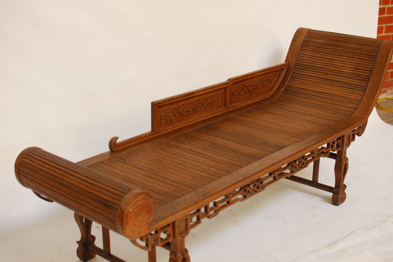 An Asian carved wood daybed, chaise longue with delicate carved legs and intricate fretwork on the aprons. The surface has a roll top look with a faux scrolled end, and the armrest features carved dragons. A very unique piece of furniture from a San