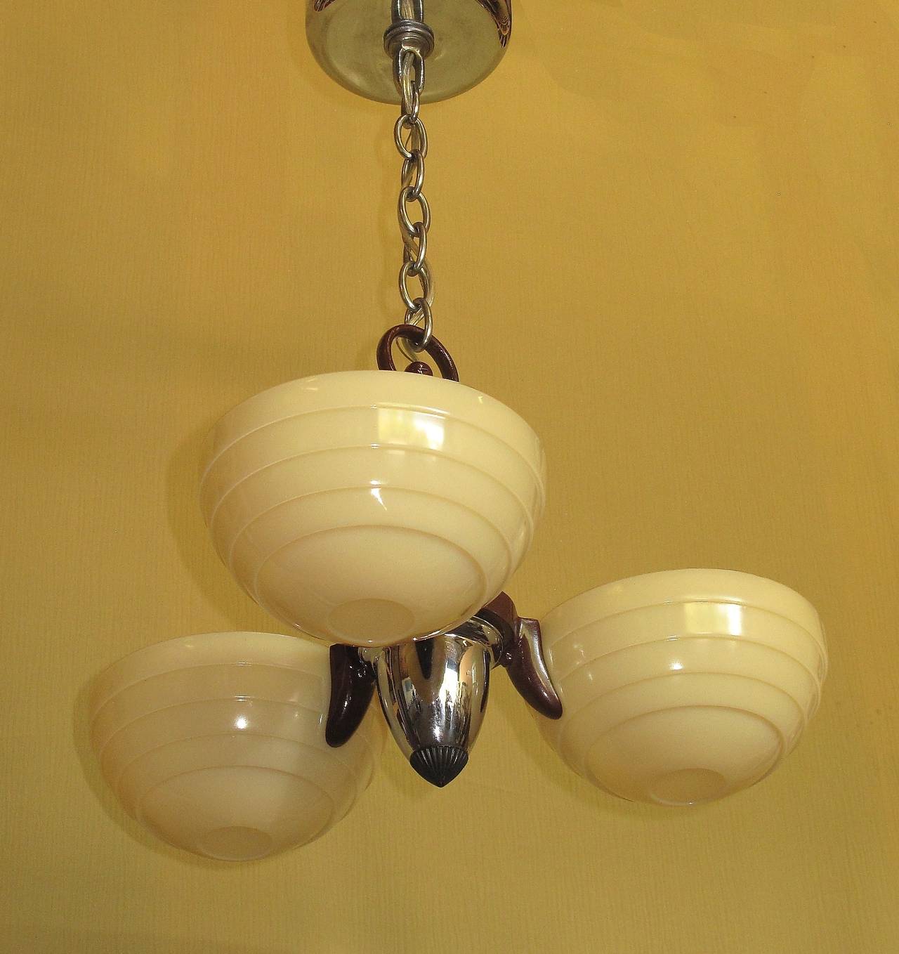 From the 1930s comes a hard charging example of the changing design trend towards what we now call Mid-Century. Three-light ceiling fixture with original custard glass shades with all three shades in excellent condition. The chrome pieces have all