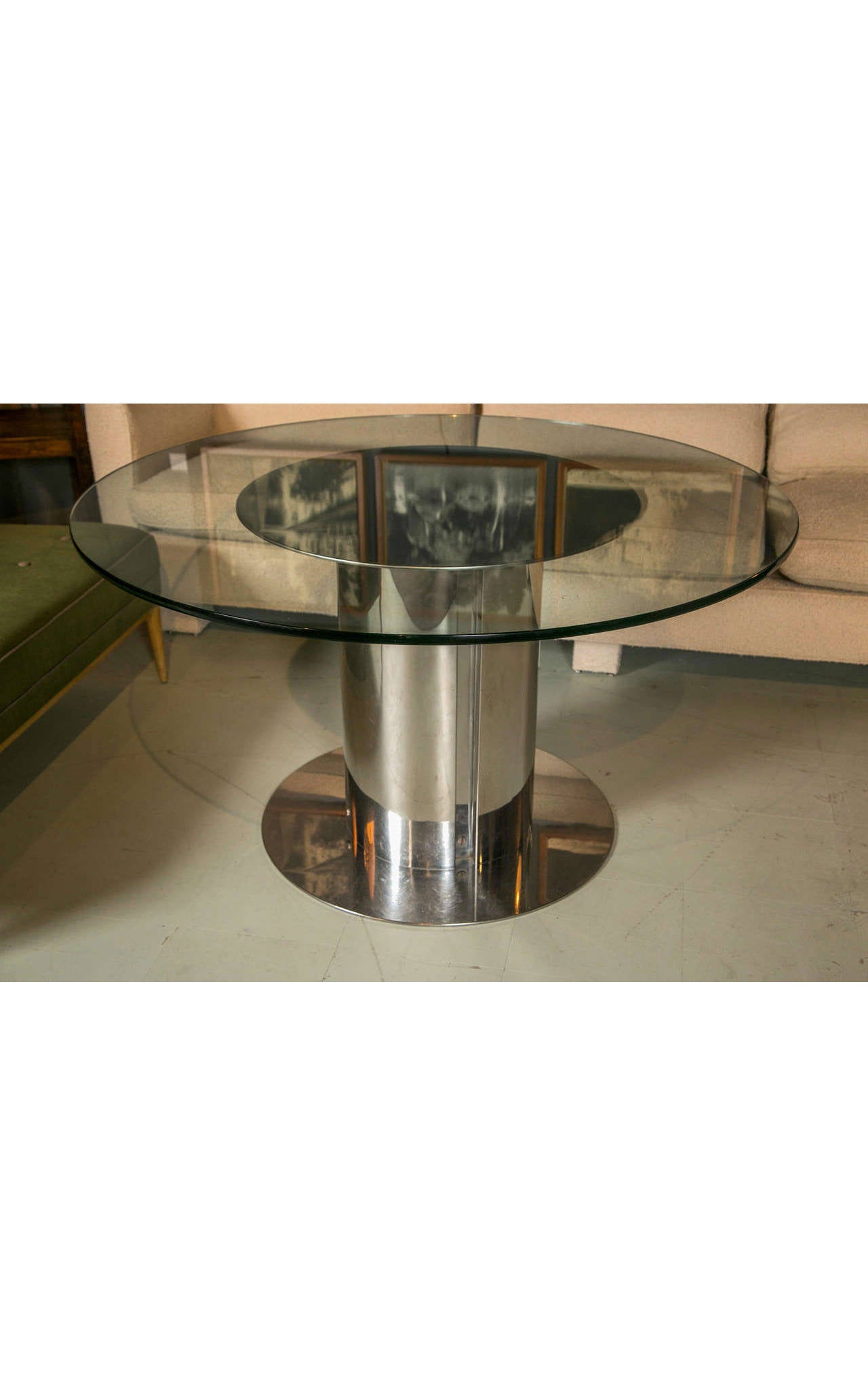 This round dining table is composed of a glass top and a polished chrome pedestal base. It's a simple but very striking design that creates the effect of spaciousness, with the mirror-quality of the chrome and the transparency of the glass.