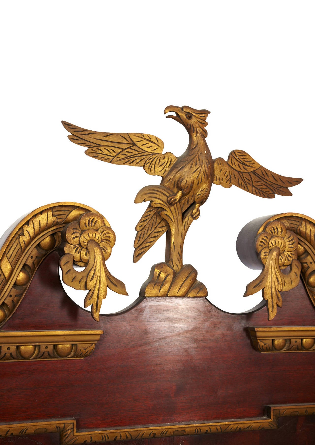 The chippendale style of this mirror is a balance of simplicity and ornamentation. The mirror itself is rectangular and set into russet colored and gold tinted frame. A phoenix-eagle adorns the pediment, flanked by elaborate carved arches.