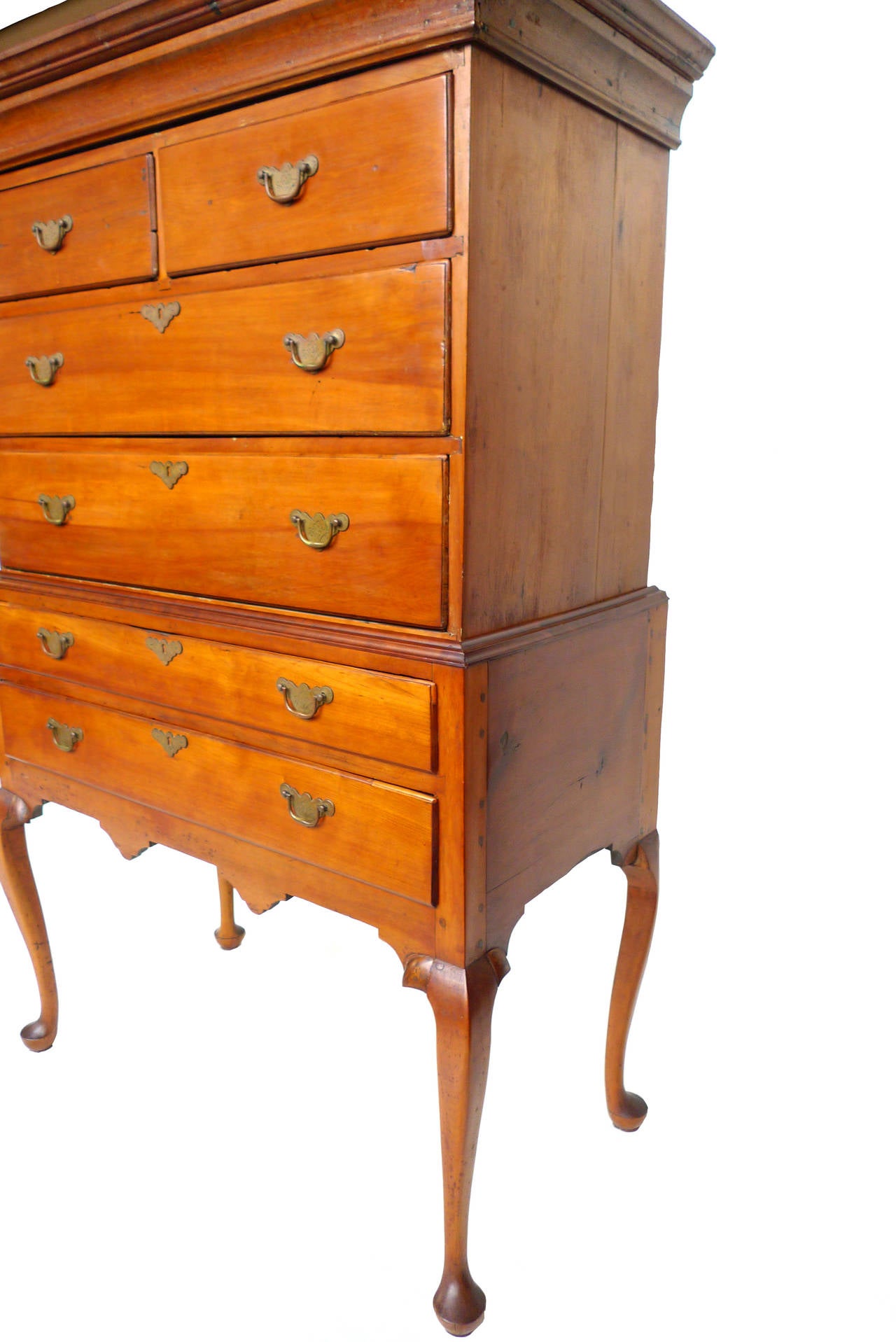 Like many Queen Anne-styled Connecticut highboys (circa 1740-1760), this flattop piece has an elegant and austere design. Dovetailed joints characterize its stabile and sturdy build, constructed from tiger maple and heart-pine wood. Brass pulls with