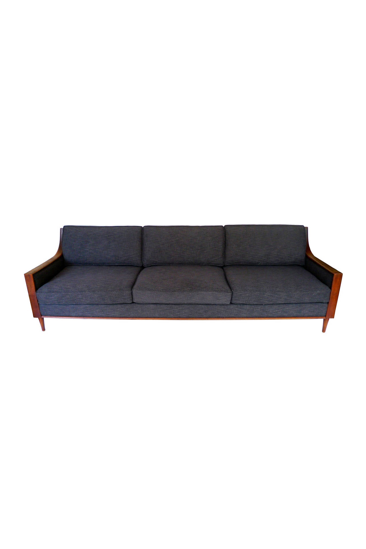 This handsome Mid-Century sofa is newly re-cushioned and reupholstered in dark, bluish gray cotton from Duralee. The arms are a beautiful deep brown teak and dramatically slope up to the back. The six-inch legs are also teak and taper downward. This