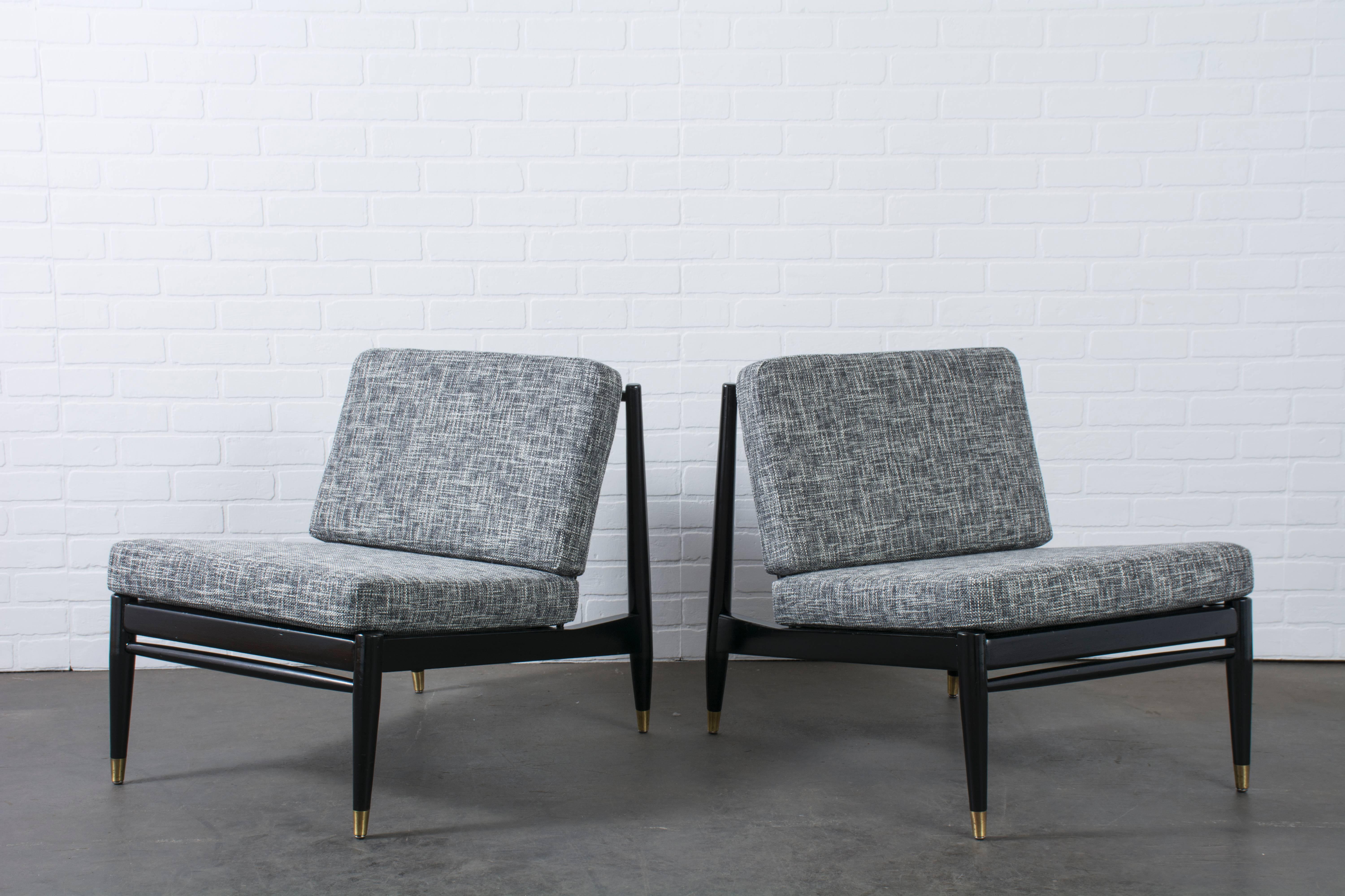 This is a pair of vintage Mid-Century lounge chairs with black frames, gold accents and new black and white upholstery.