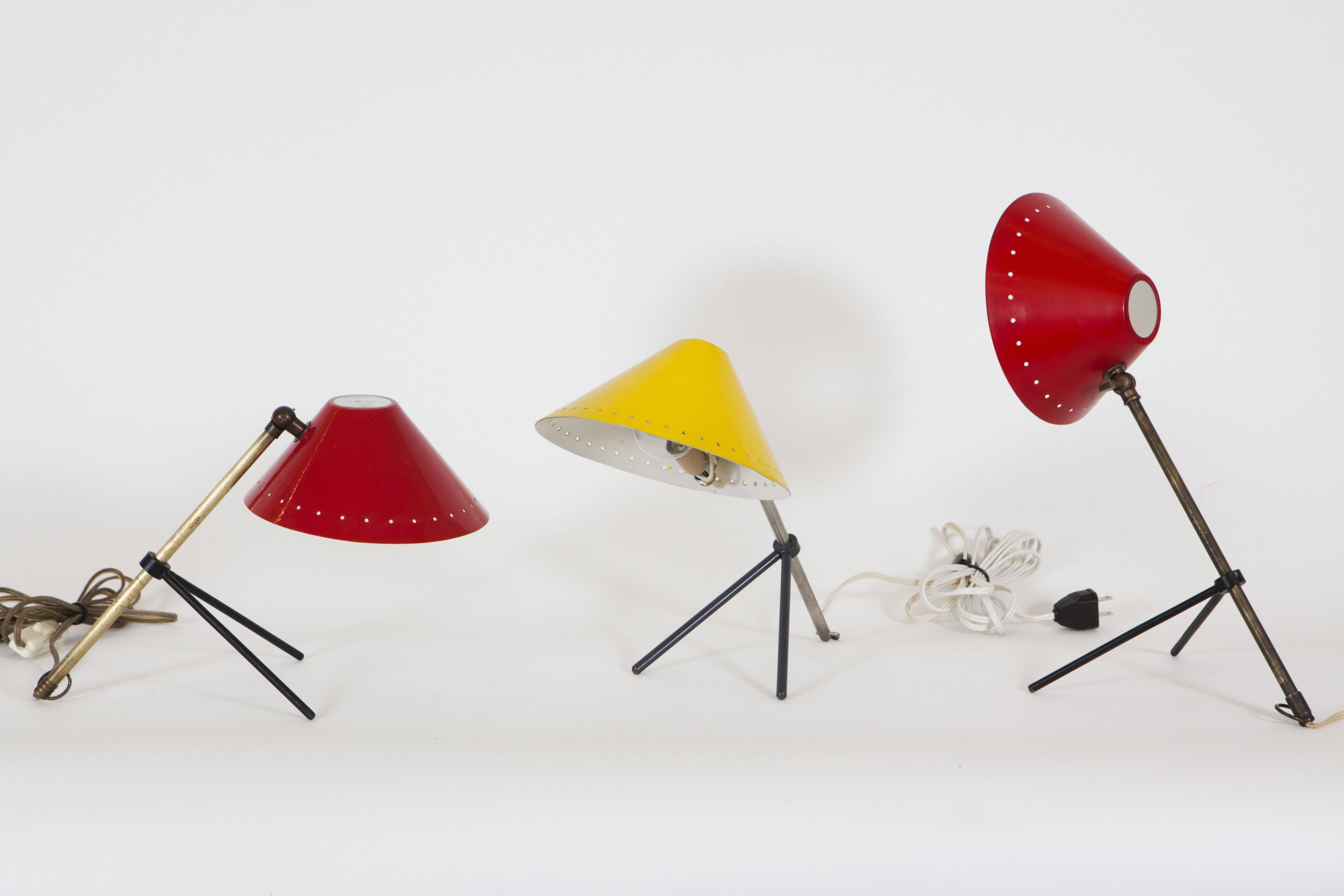 Hala Zeist Pinocchio lamps by H.Th.J.A. Basque. These function as a table or wall light. The light can be directed by adjustment to the metal tripod base with the colored metal shade. The yellow light is decorated with the cut shape pattern around