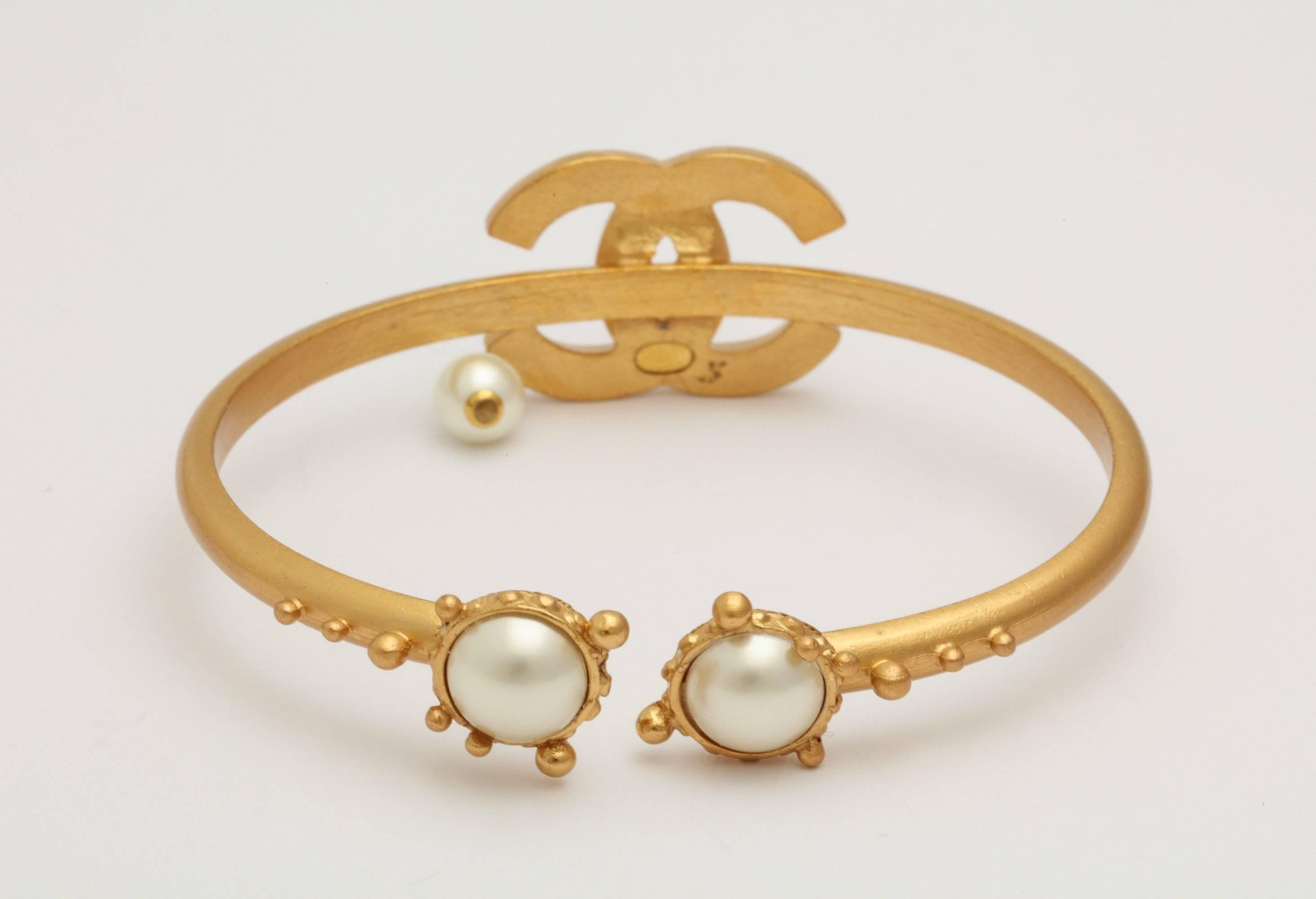 A rare vintage Chanel bangle with CC encrusted opaline crystals and a 
dangling pearl .  The underside  has the CC logo with a pearl surrounded by
etruscan style bead work. This is adjustable for most wrist sizes.
