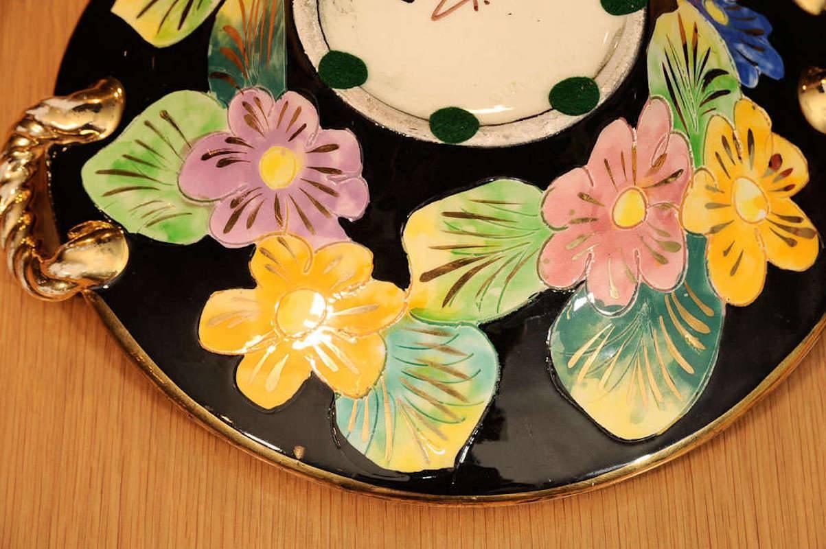 Stamped and signed ceramic dish with handles, large flower design on black field with gold details.