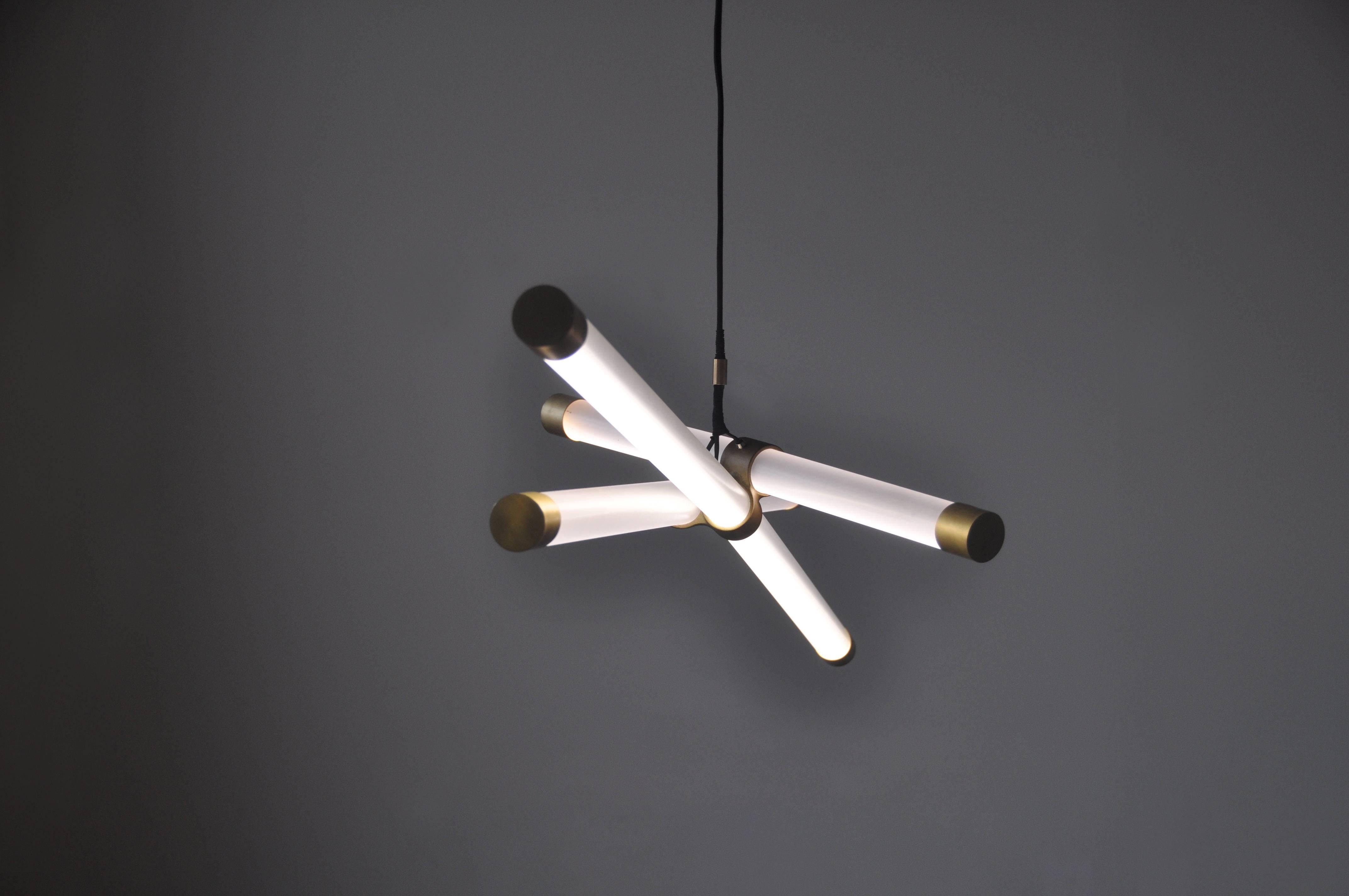 The Hanging Axis Light is a modular lighting fixture that relies on its center of gravity to maintain equilibrium. 

The brushed brass connector holds each dimmable LED tube in place while the handmade end caps create the piece visually balanced.