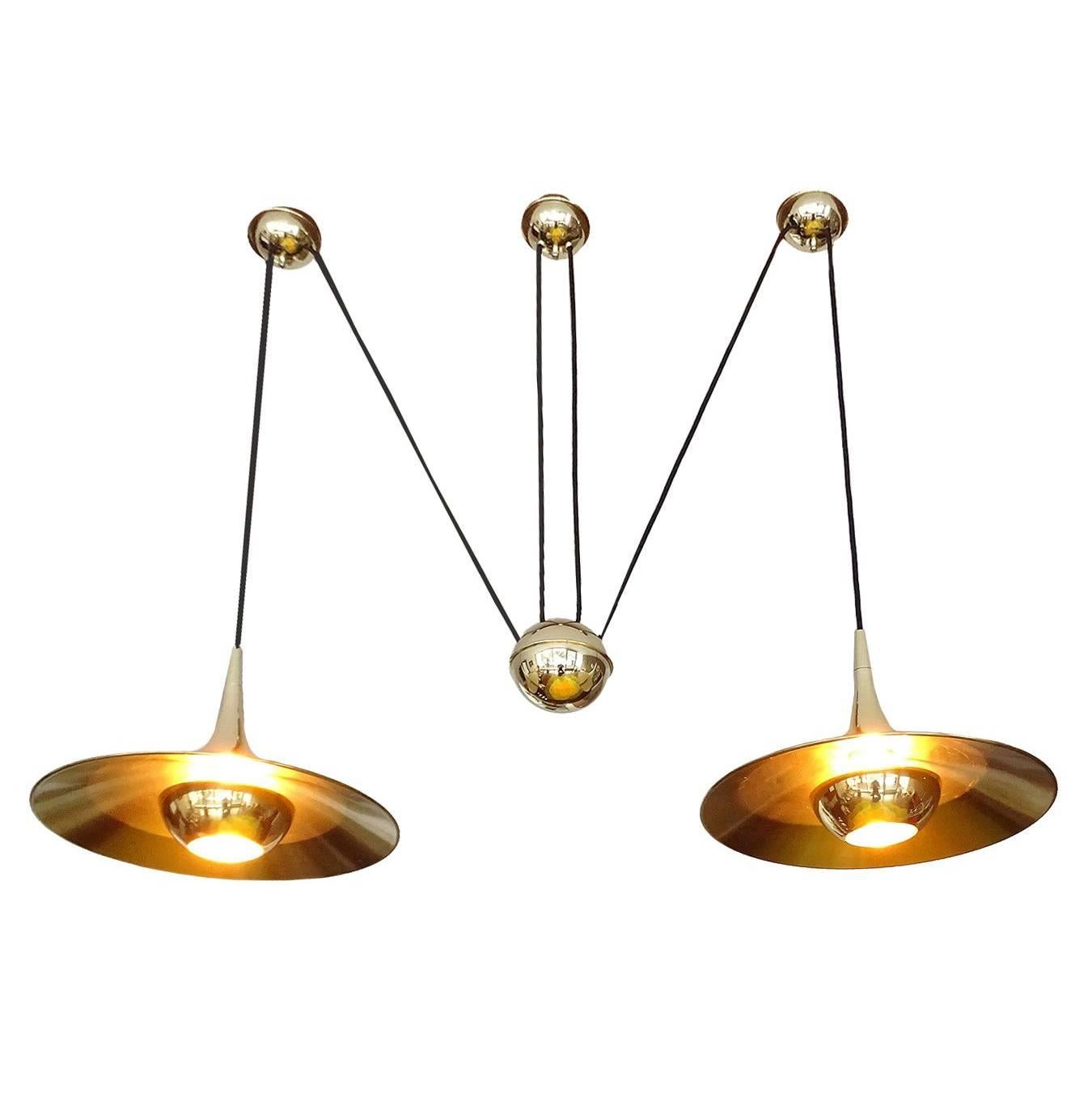 Very large dual brass chandelier pendant light with central adjustable pull counterweight, high end quality polished brass and matte finish inside the shade for smooth spread of the light, glare free construction with bulb hiding caps. The light can