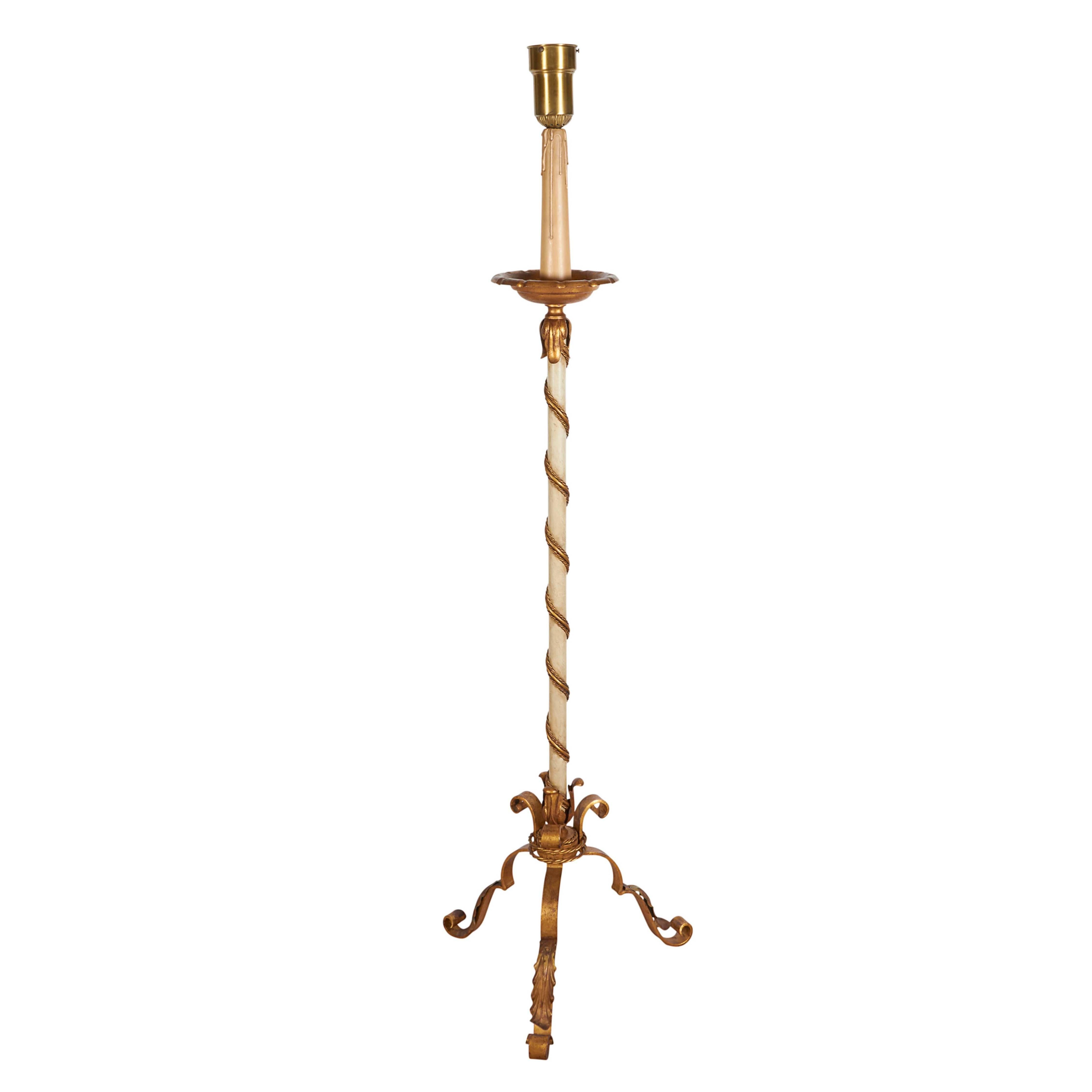 A vintage floor lamp in the Hollywood Regency manner, single socket brass diffuser and wood painted faux wax holder with decorative bobeche on white enamel stem with serpentine rope motif, raised on scroll tripod base in gilt metal, with acanthus