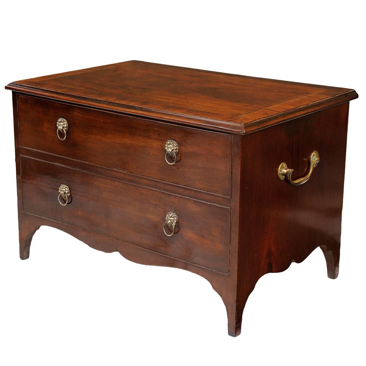 This is a rather striking English late 18th century George III Cellarette chest, featuring a beautiful cross banded mahogany top, with two dummy drawers to the front, smart brass lion head handles and complete with brass carrying handles. The