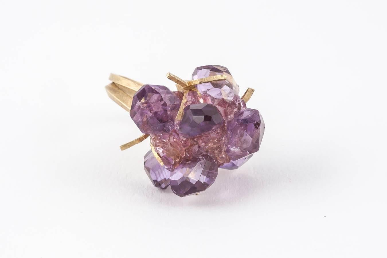 18ct Gold hand-crafted Donna Brennan Cocktail Ring. Featuring unusual facetted Amethyst stones & crushed Pink Tourmaline with 2 matt gold ring shanks entwined in a size 6 ( L ).

Donna's work typically features sculpturally wrapped rings hewn from
