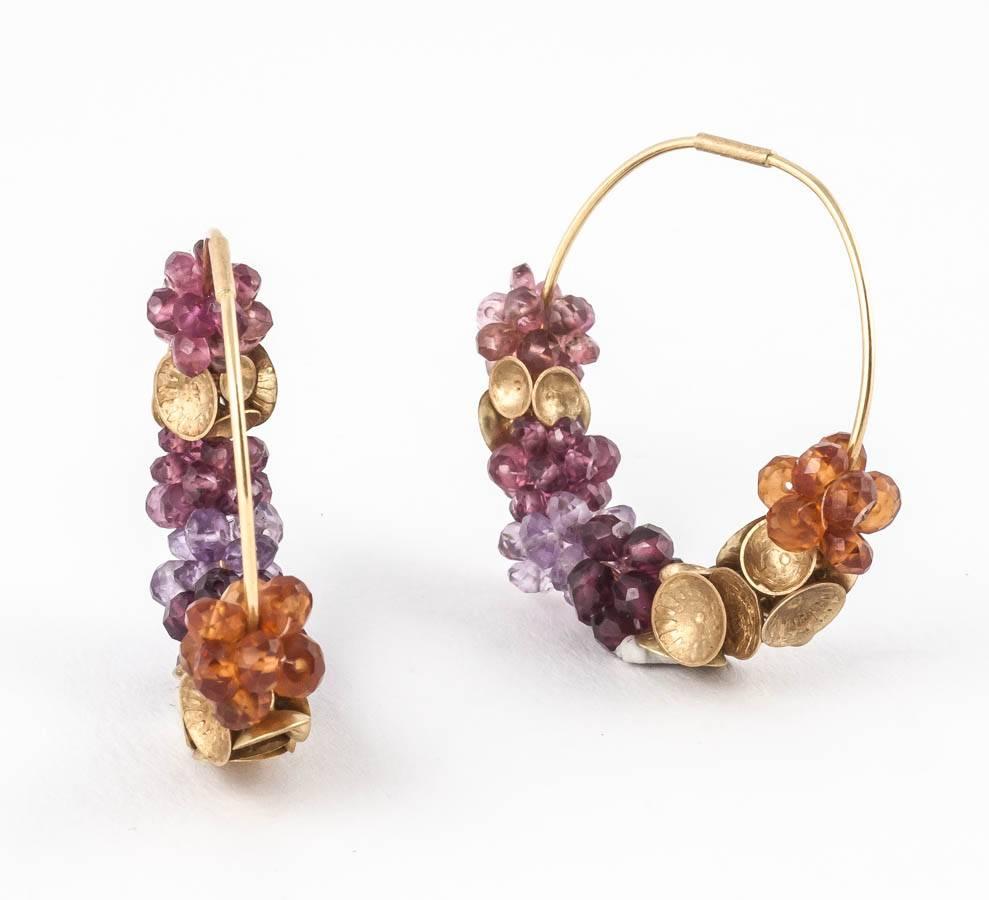 18ct matt Gold Donna Brennan Earrings deliciously encrusted with Garnet, Pink Tourmaline, Rhodolite Garnet, Citrine & Amethyst and interlaced with decorative 18ct matt gold disks. 

Donna's work typically features sculpturally wrapped rings hewn