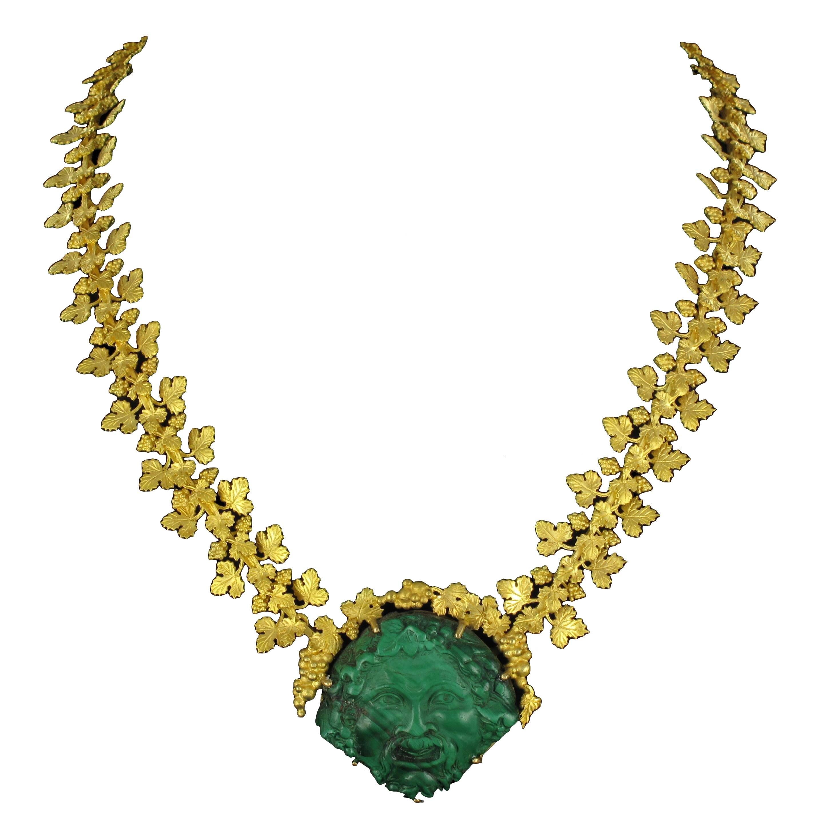 Necklace in 18K matt yellow gold necklace, eagle head hallmark.
Consisting of golden vine leaves and bunches of grapes hinged together, the centrepiece of this unusual necklace is a malachite cameo of a grinning ‘Bacchus’. The clasp is a rectangular