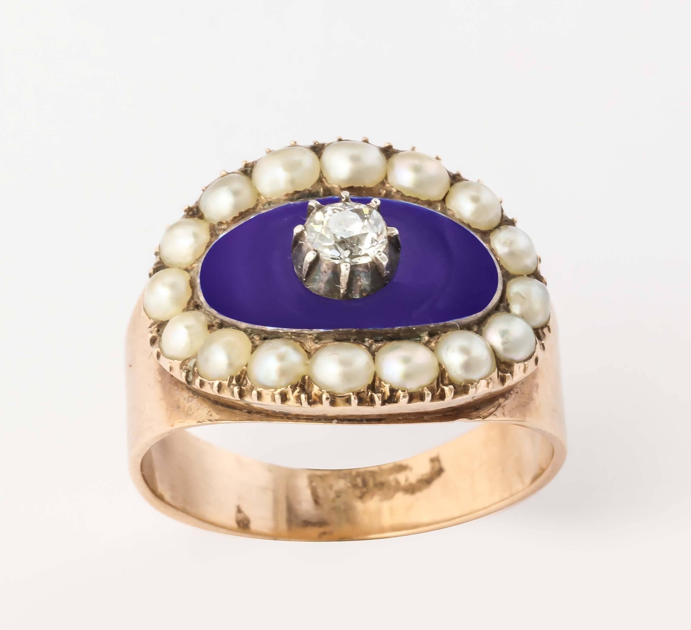 One diamond in an oval surround of sky blue is framed by perfectly matched natural pearls and set in 15kt rose gold. The shank is a cigar band, wider in front and, for comfort,  narrowing at back of the finger. For the sake of this description, the